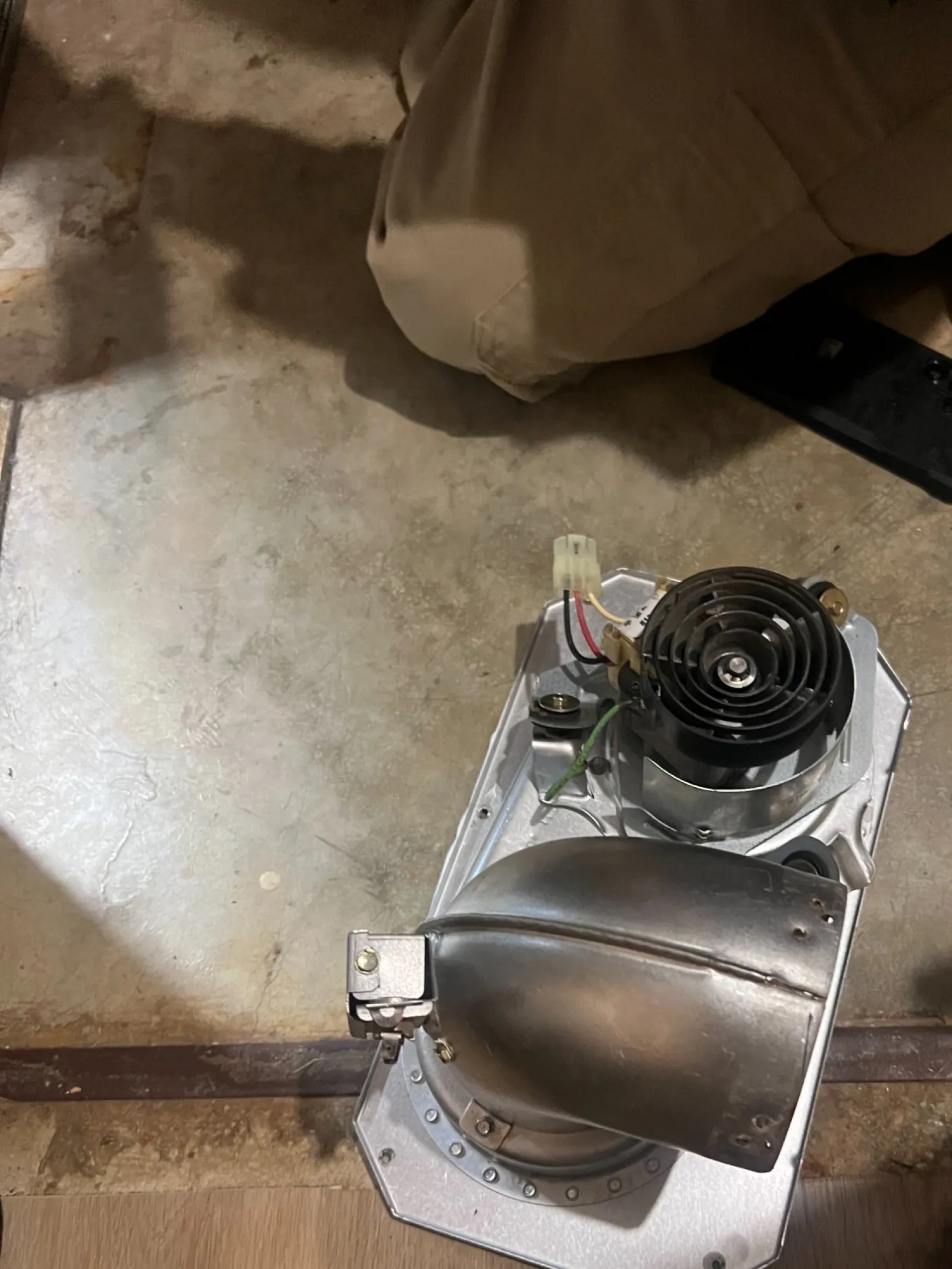 AC Cooling Repair in Atlanta Brookhaven 30319 by The Air Company of GA.  Mechanical ventilation fan assembly placed on a concrete floor between two knees and tools.