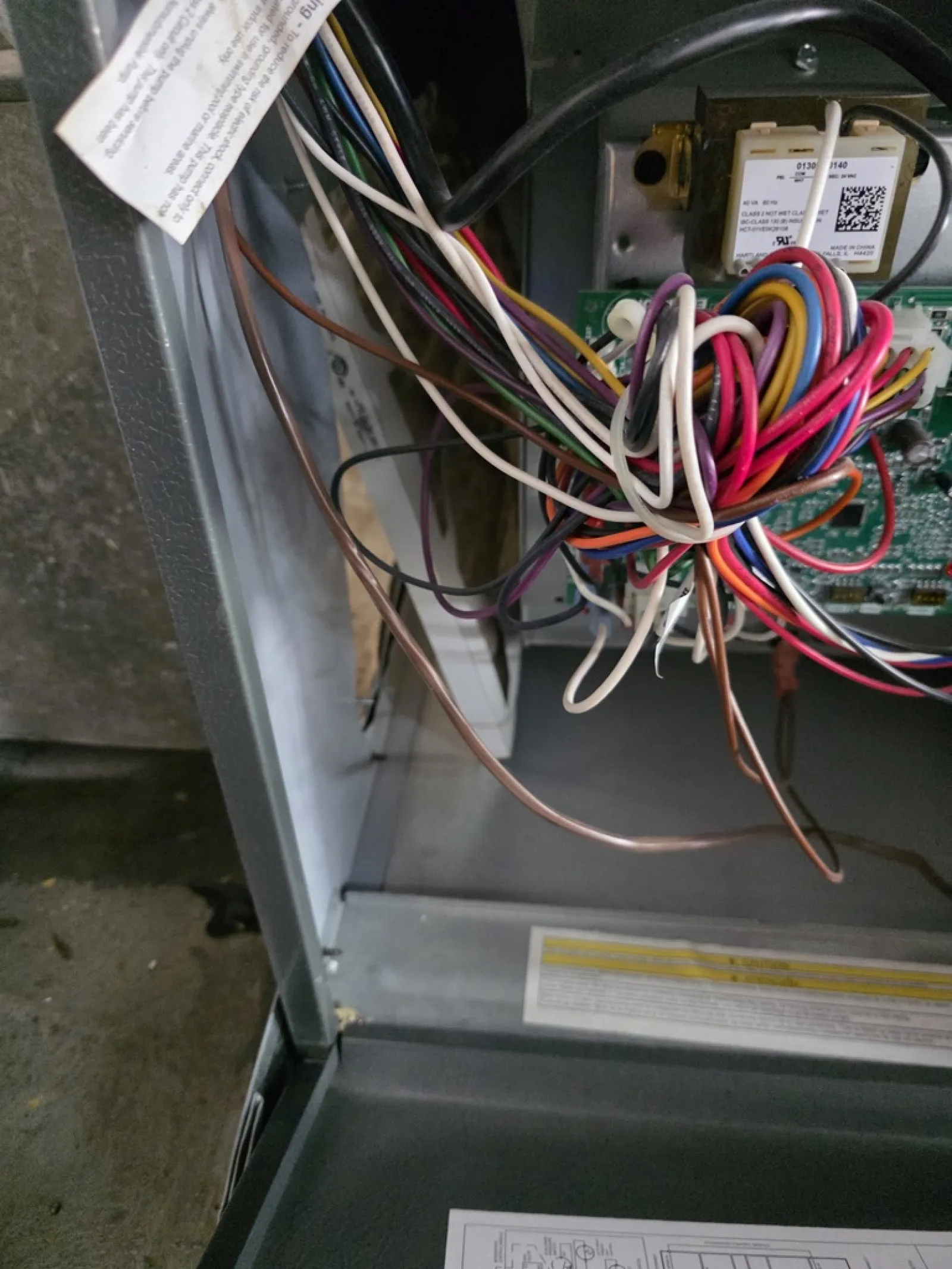 Open electrical panel with multicolored wires connected to circuit board inside metal enclosure.