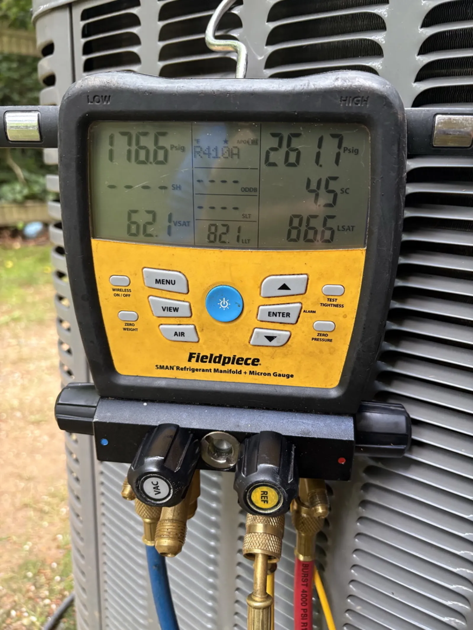Fieldpiece SMAN refrigerant manifold gauge displaying pressure and temperature readings on HVAC unit.