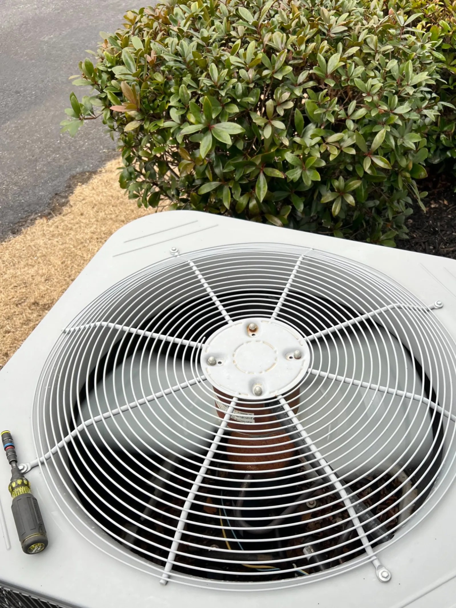 AC Repair in Roswell 30076 by The Air Company of GA.  Outdoor central air conditioning unit with large fan and protective grill sitting near shrubbery.