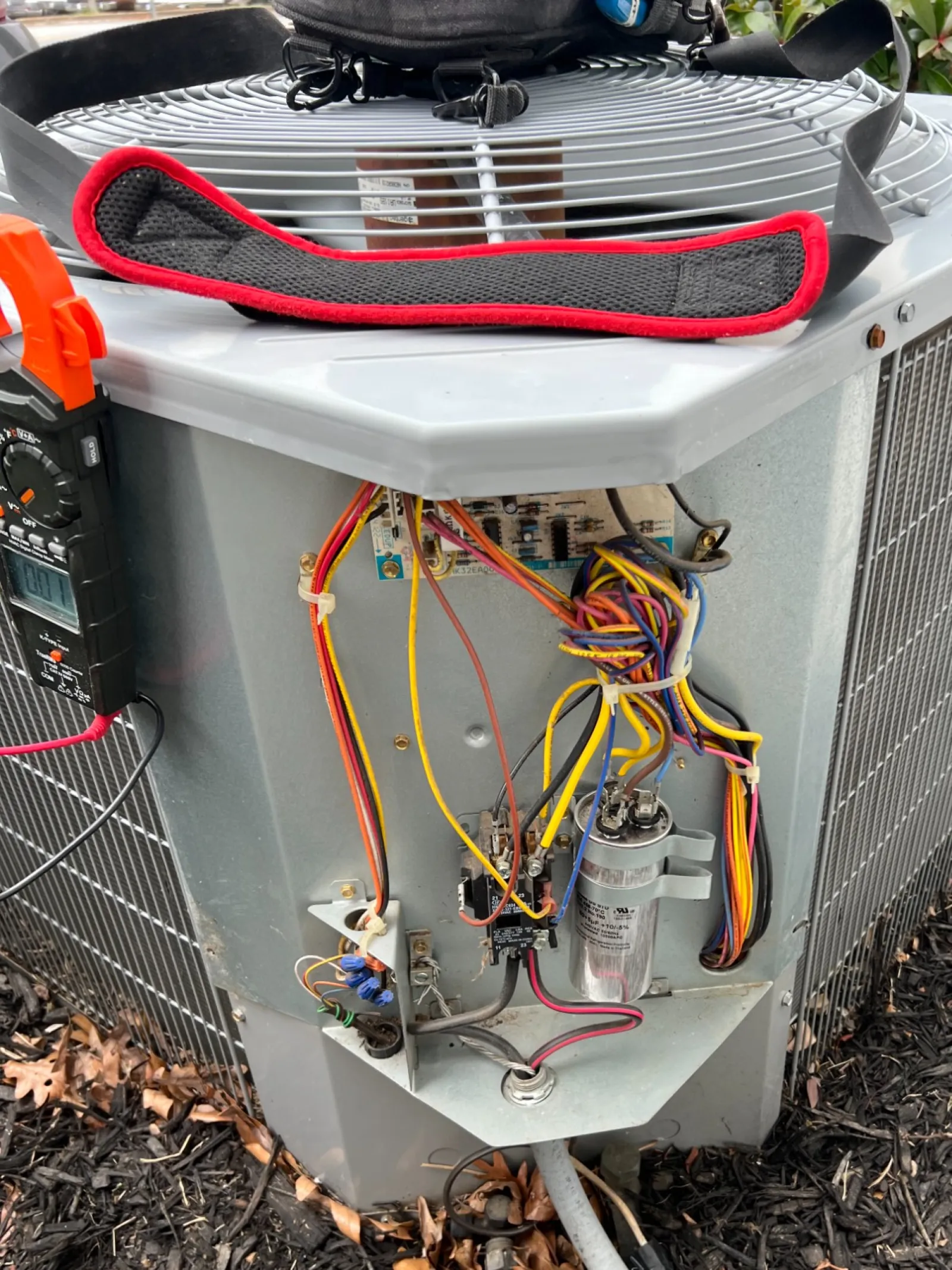 AC Repair in Roswell 30076 by The Air Company of GA. Outdoor HVAC unit with open panel showing internal wires, capacitor, and electrical connections on mulch ground.
