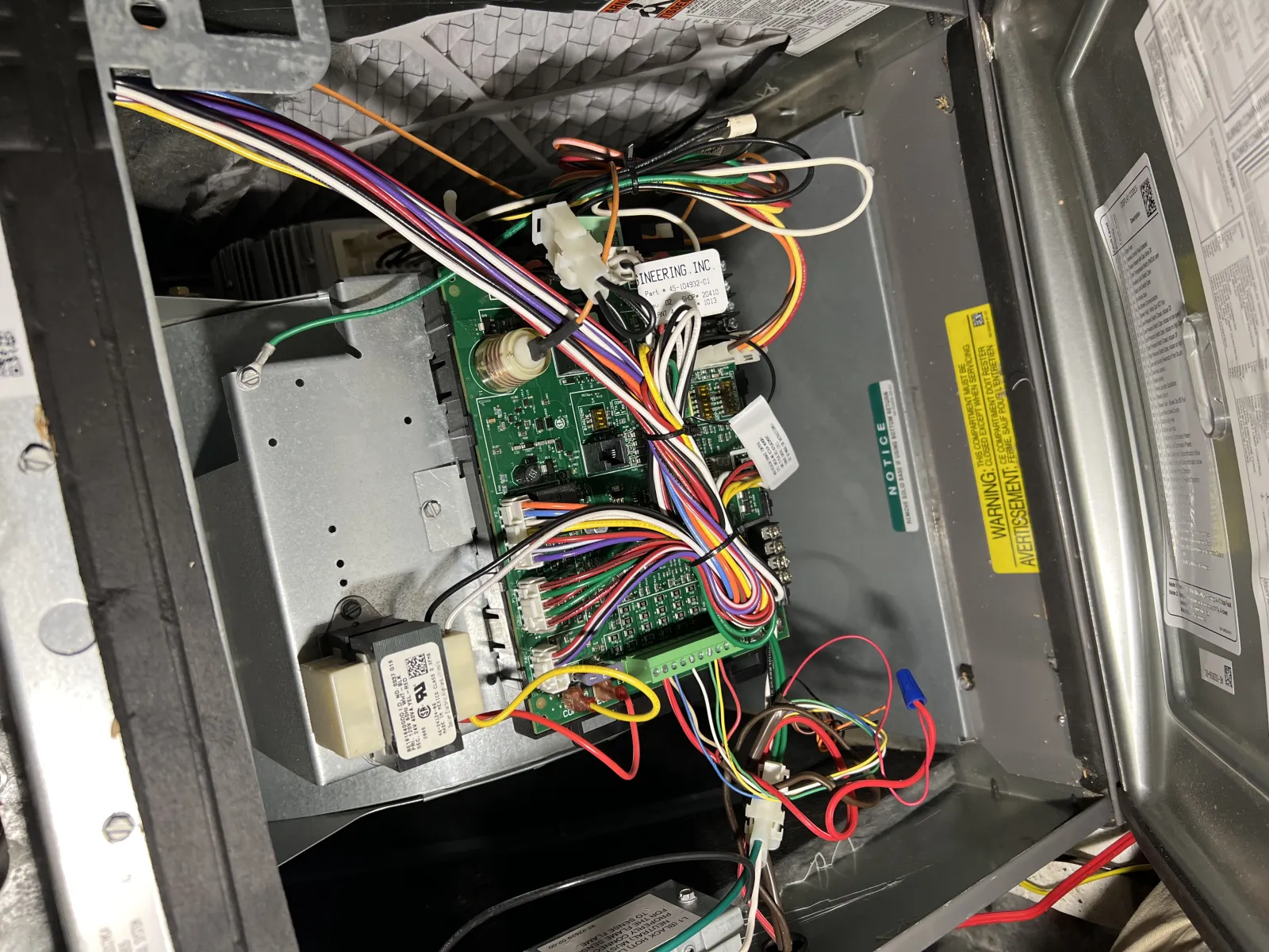 Open electronic control box with colorful wires connected to a green circuit board inside a metal casing.