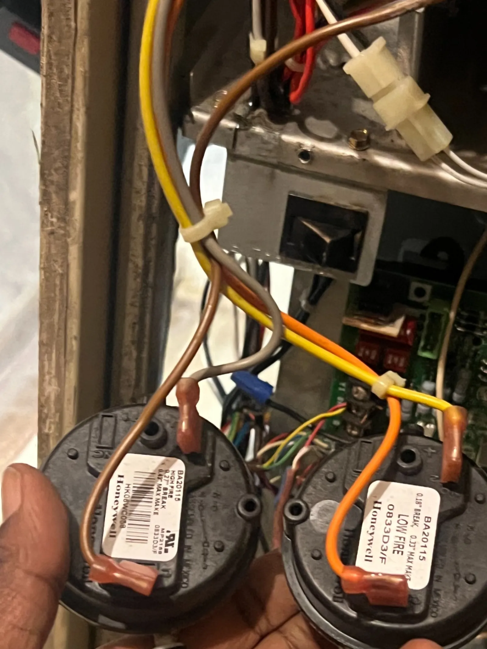 AC Cooling Repair in Atlanta Brookhaven 30319 by The Air Company of GA.  Hand holding Honeywell low and high fire pressure switches with connected wires inside HVAC system.