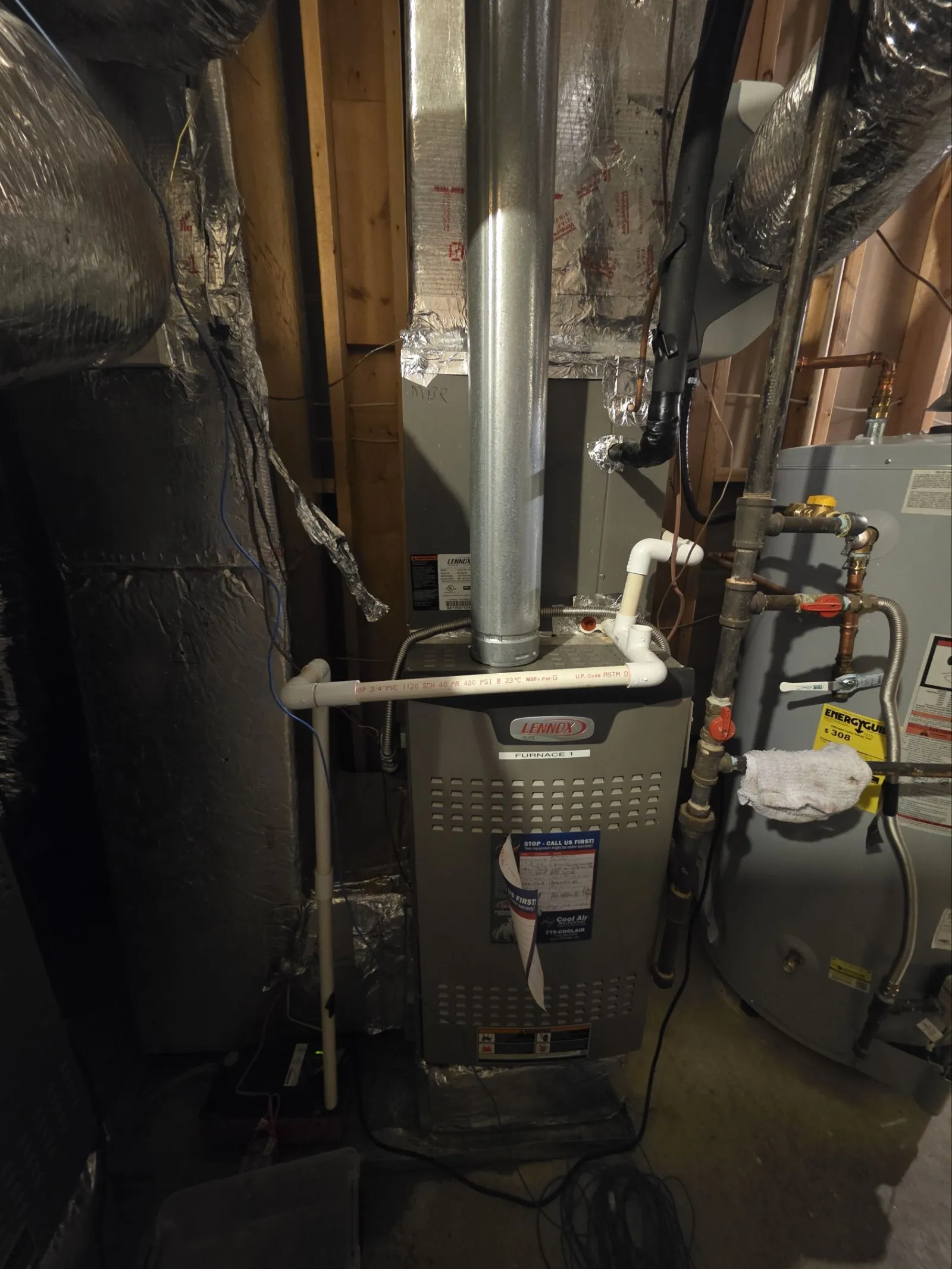 Residential AC Cooling Repair in Atlanta 30327 by The Air Company of GA.  Lennox furnace and water heater setup in a home's utility area with pipes and insulation visible.