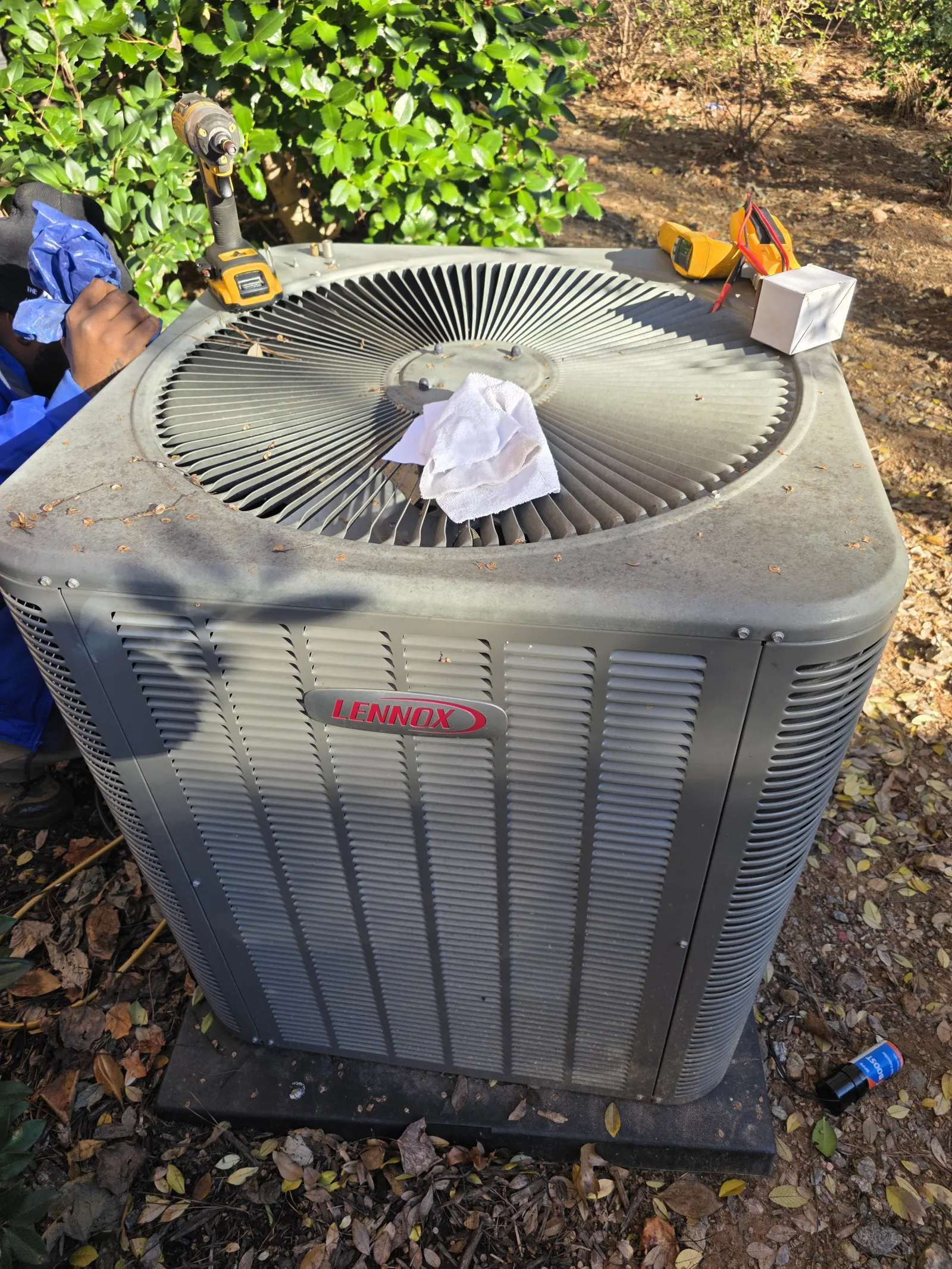 Residential AC Heat Repair in Marietta 30068 by The Air Company of GA.  Outdoor Lennox air conditioning unit with tools and technician working nearby in a garden setting.