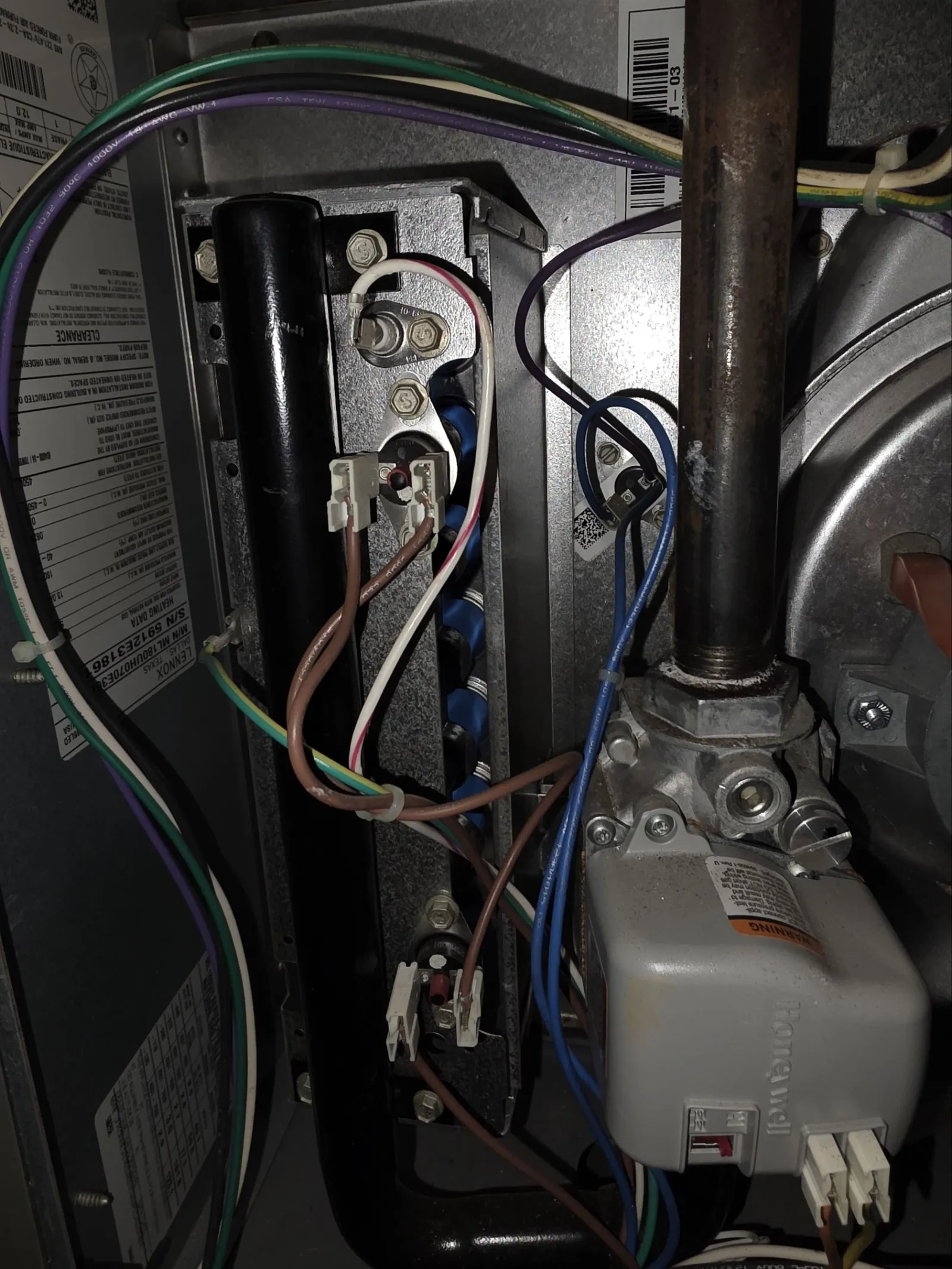 Residential AC Cooling Repair in Atlanta 30318 by The Air Company.  Inside view of furnace electrical wiring and components with various colored wires and metal pipes.
