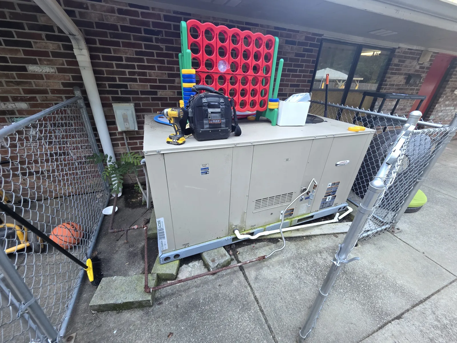 Commercial HVAC Heating Repair in Roswell 30075 by The Air Company of GAar a brick wall and chain link fence.