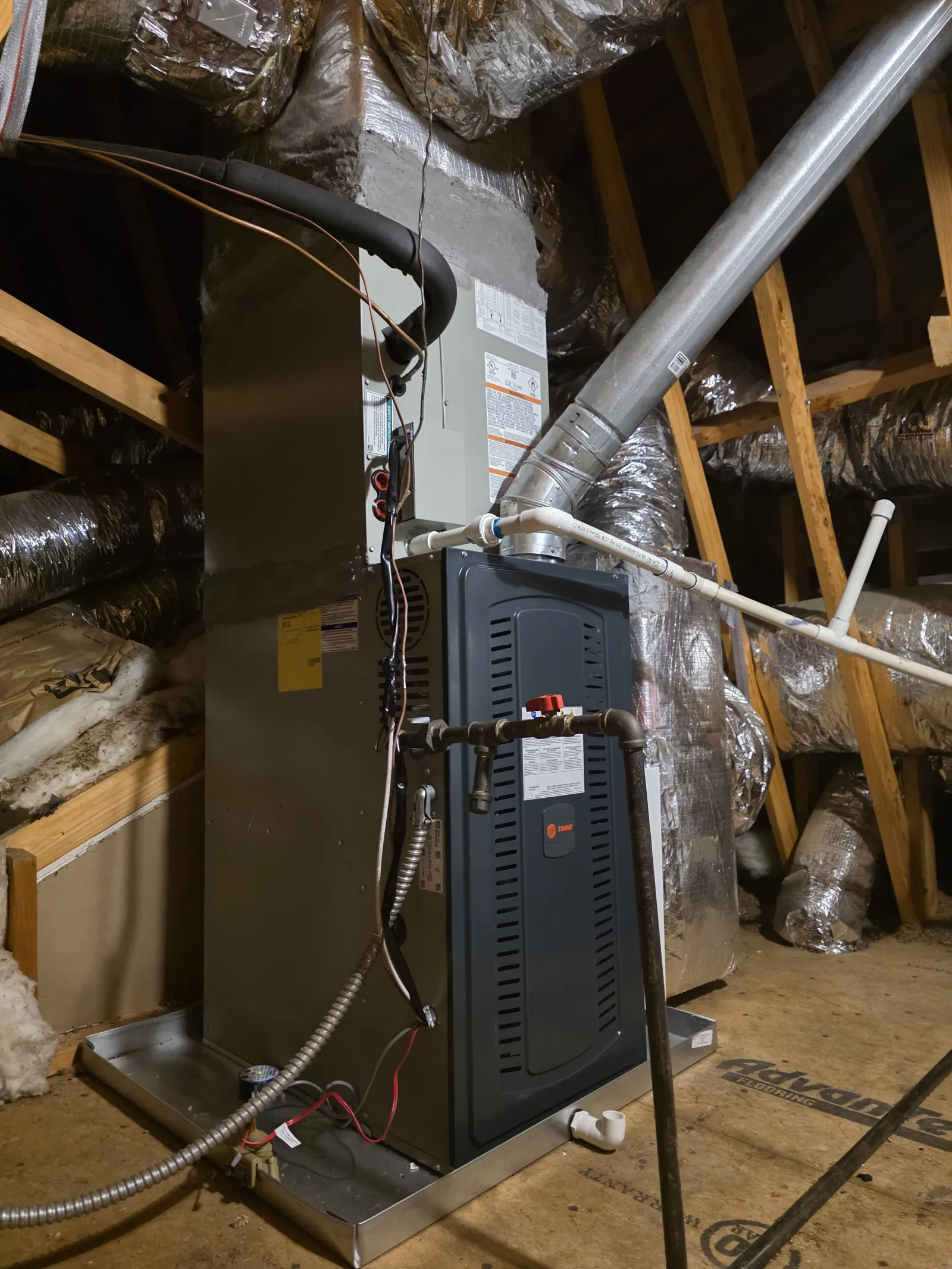 Modern HVAC furnace unit installed in attic with insulated ducts and wooden framing visible