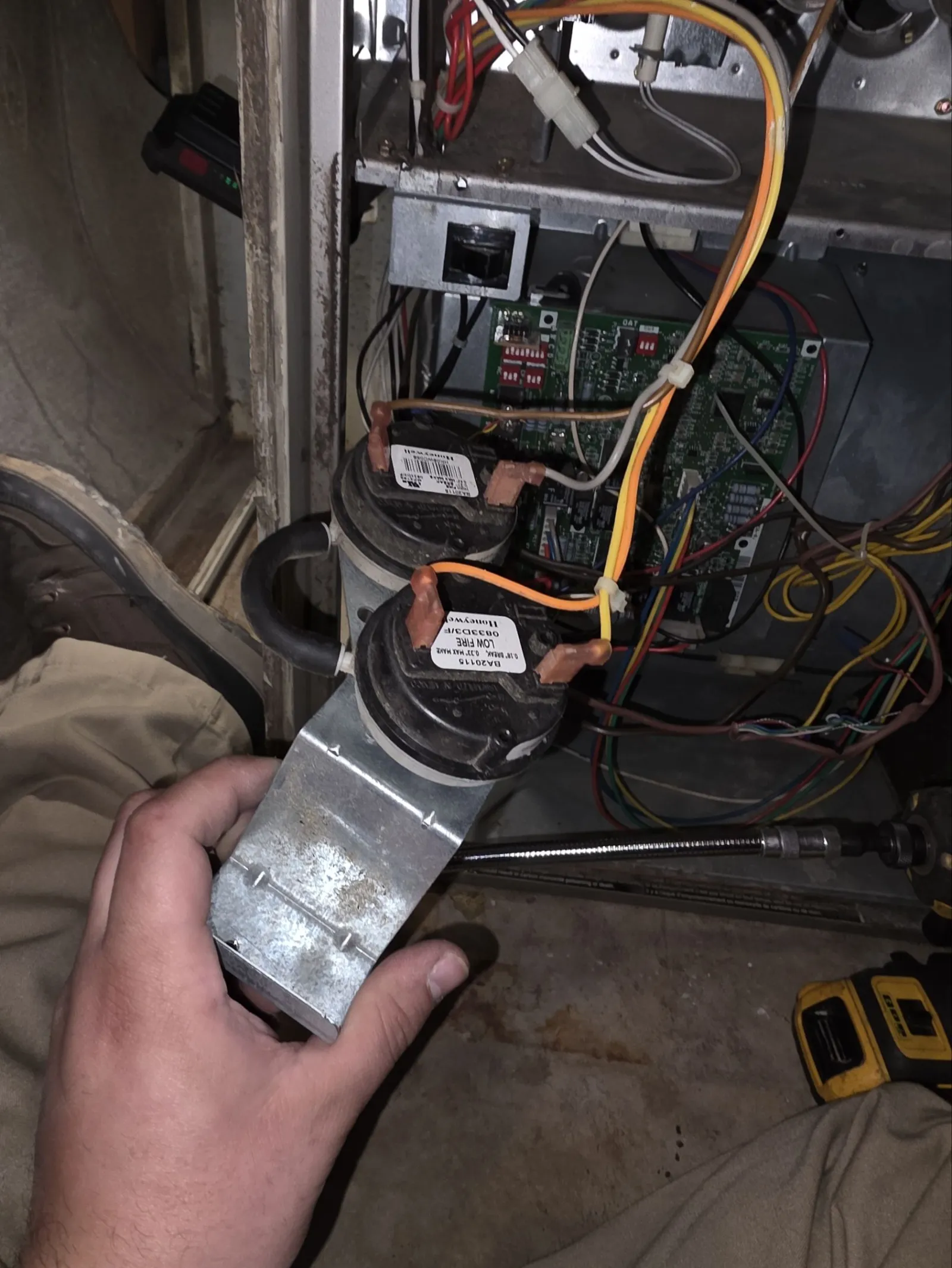 Air Conditioner AC Cooling Repair in Atlanta 30305 by The Air Company of GA. Hand holding a dual pressure switch with wires inside an open furnace electrical panel with circuits and wiring.