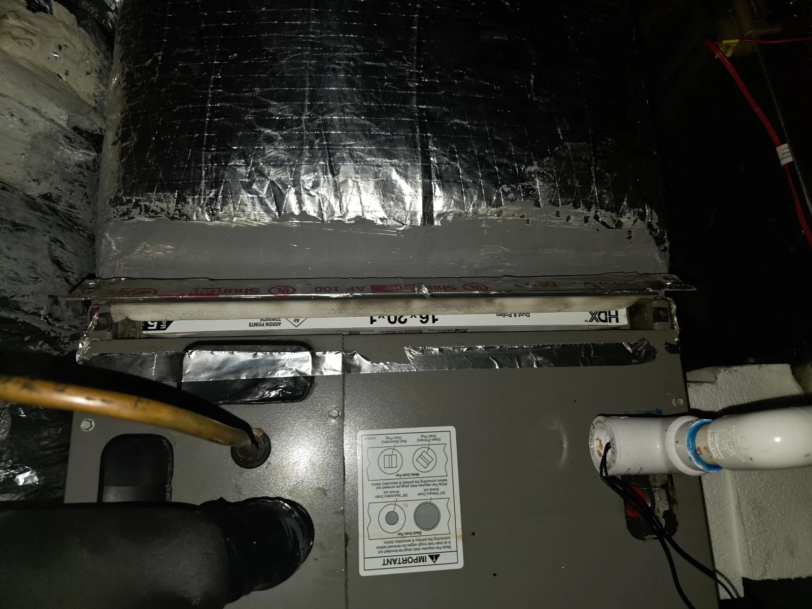 Furnace unit with insulated ductwork and connected PVC pipes in a basement HVAC system