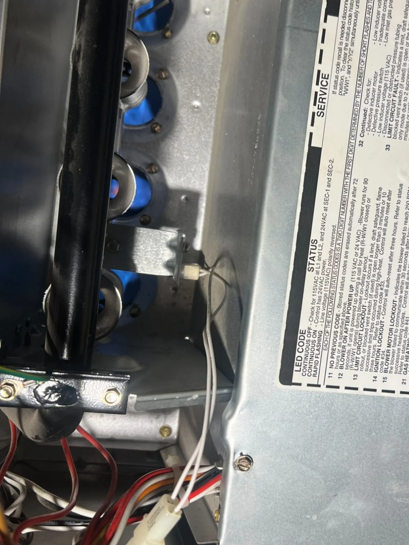 Smyrna AC Cooling Repair in Atlanta 30080 by The Air Company of GA. Inside view of a gas furnace showing burners, control wiring, and service label on metal casing.