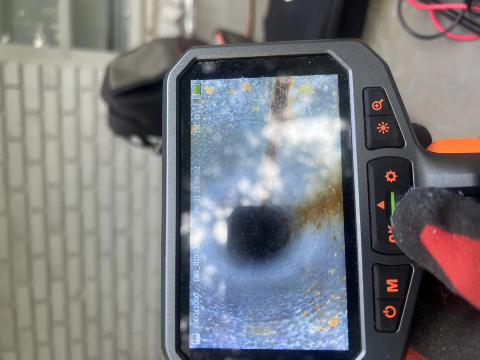 Inspection camera screen displaying the interior of a pipe with rust and debris.