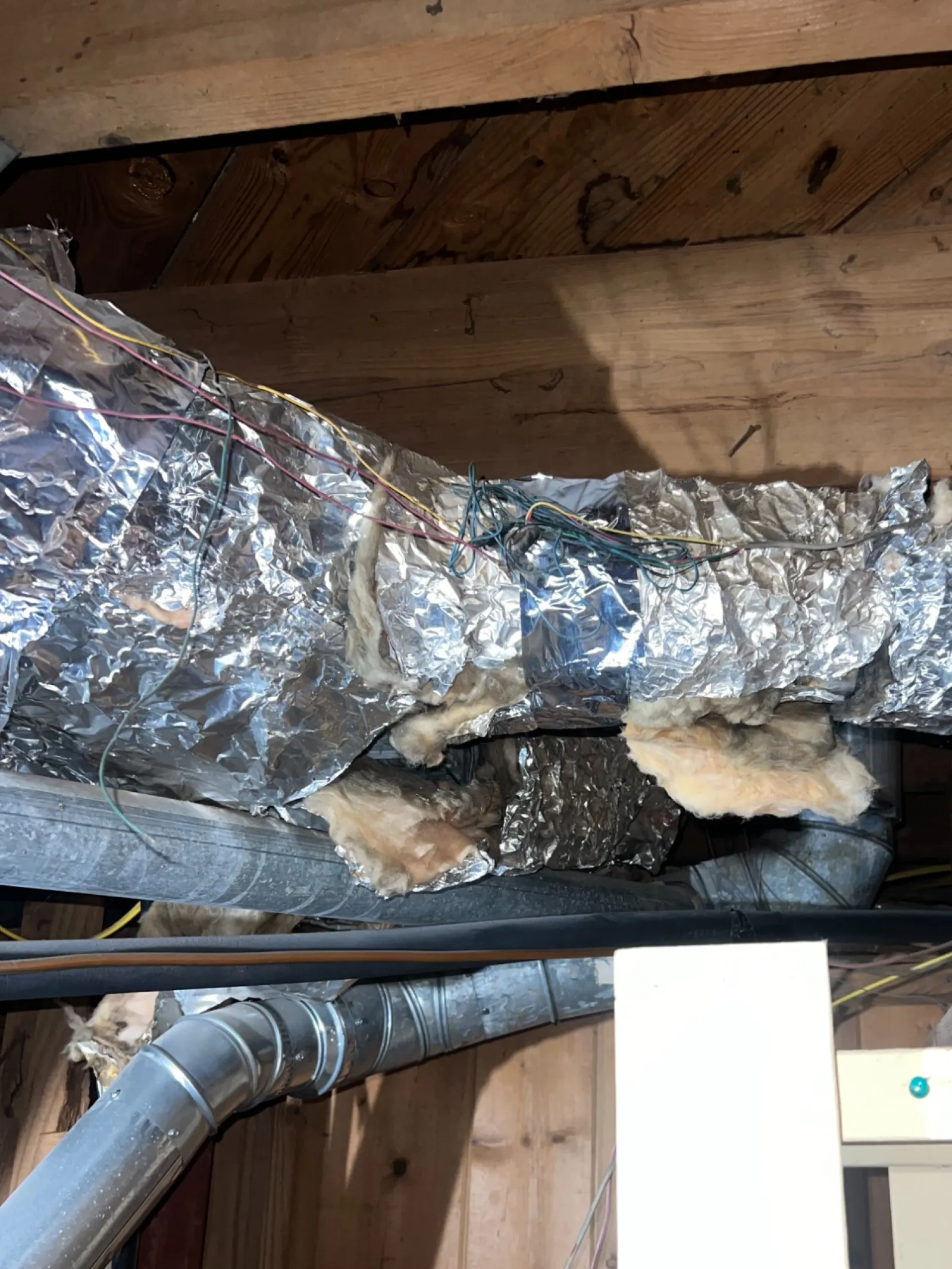 Smyrna AC Cooling Repair in Atlanta 30080 by The Air Company of GA. Insulated HVAC ductwork with foil wrap and exposed wooden ceiling beams in attic space.