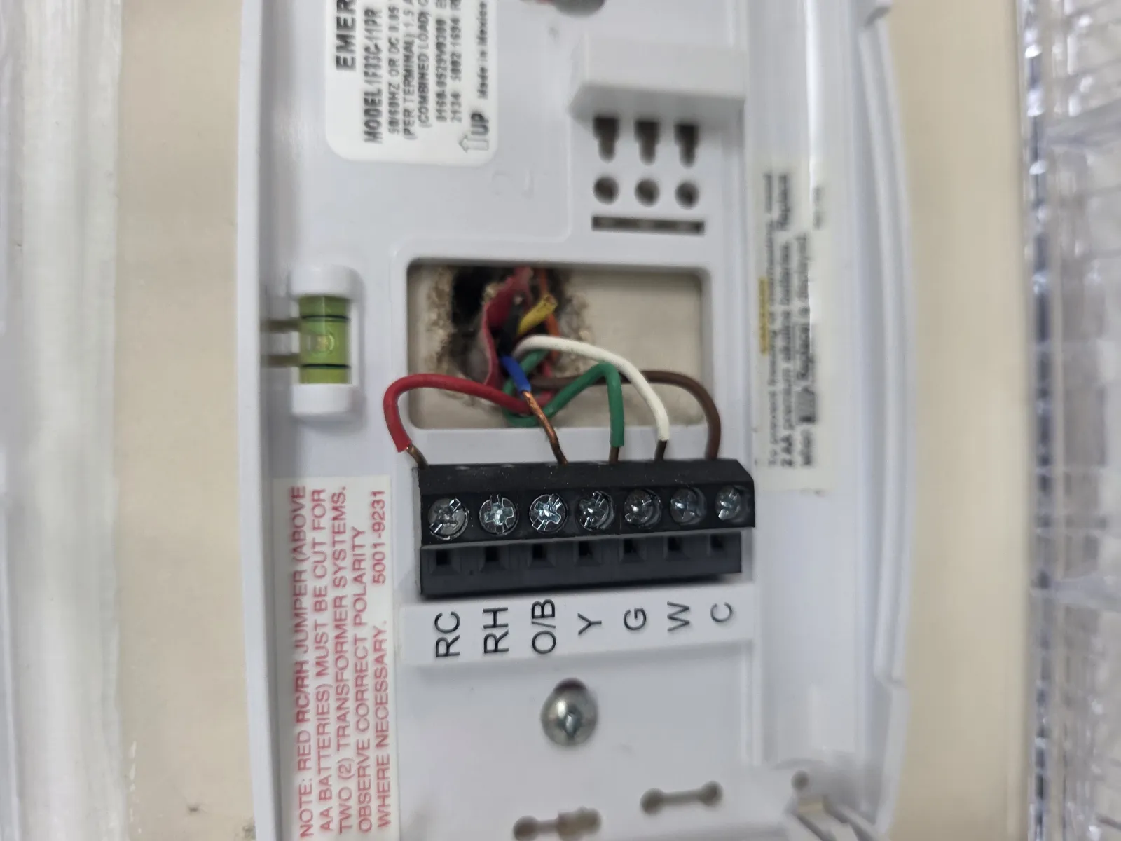 Close-up of wiring terminals inside a thermostat with labeled connectors and colored wires attached