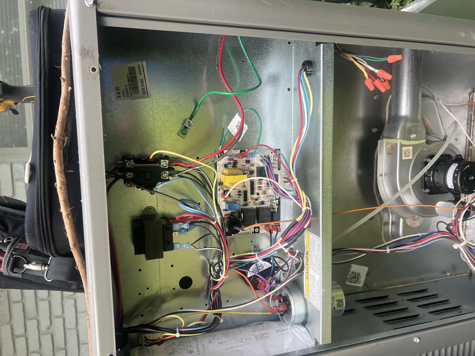Open furnace unit with multicolored electrical wires connected to circuit board and components inside metal enclosure.