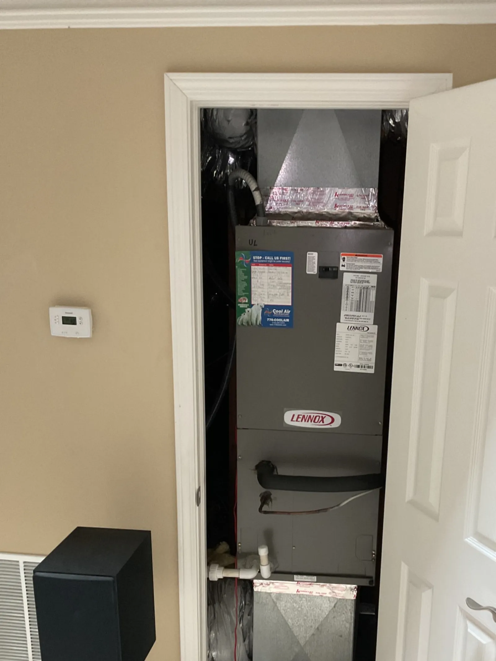 Sandy Springs Atlanta AC Repair by The Air Company of GA.  Indoor HVAC system unit with thermostat on beige wall and black speaker in room with carpet.