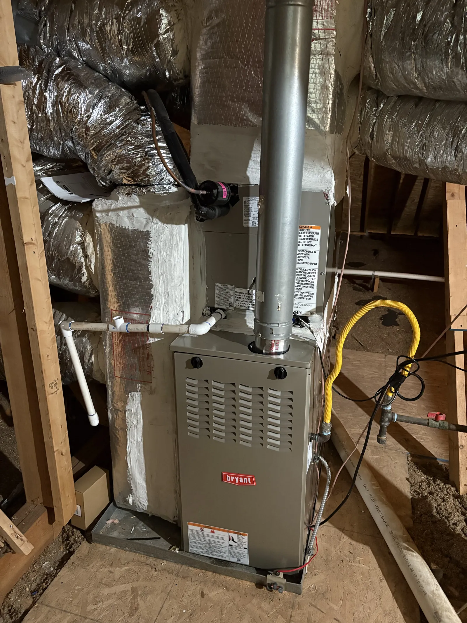 Bryant furnace unit installed in an attic with insulated ductwork and ventilation pipes