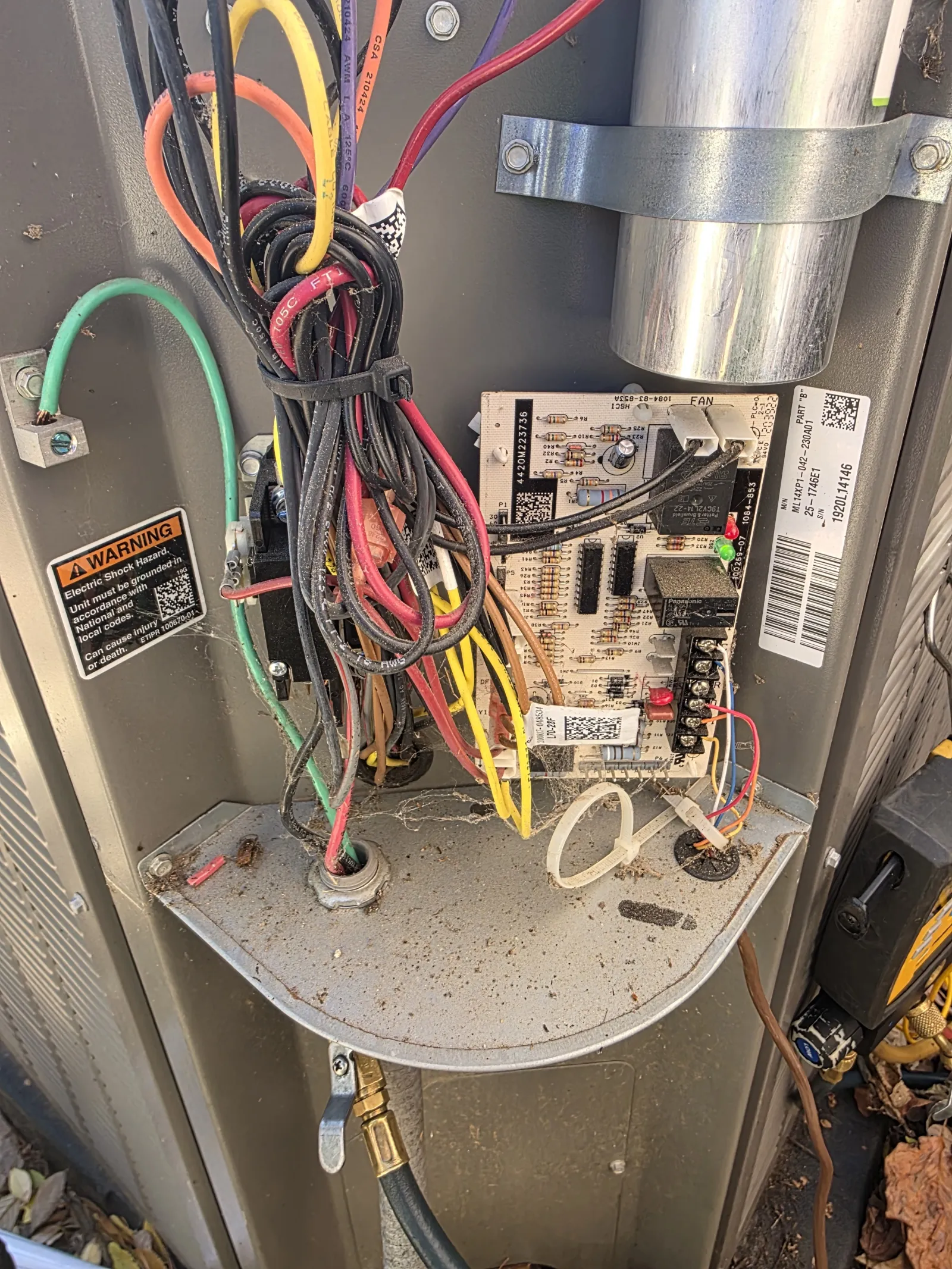 Residential AC Heat Repair in Marietta 30068 by The Air Company of GA.  Inside view of a circuit board with colorful electrical wires in a metal enclosure warning of electric shock hazards.