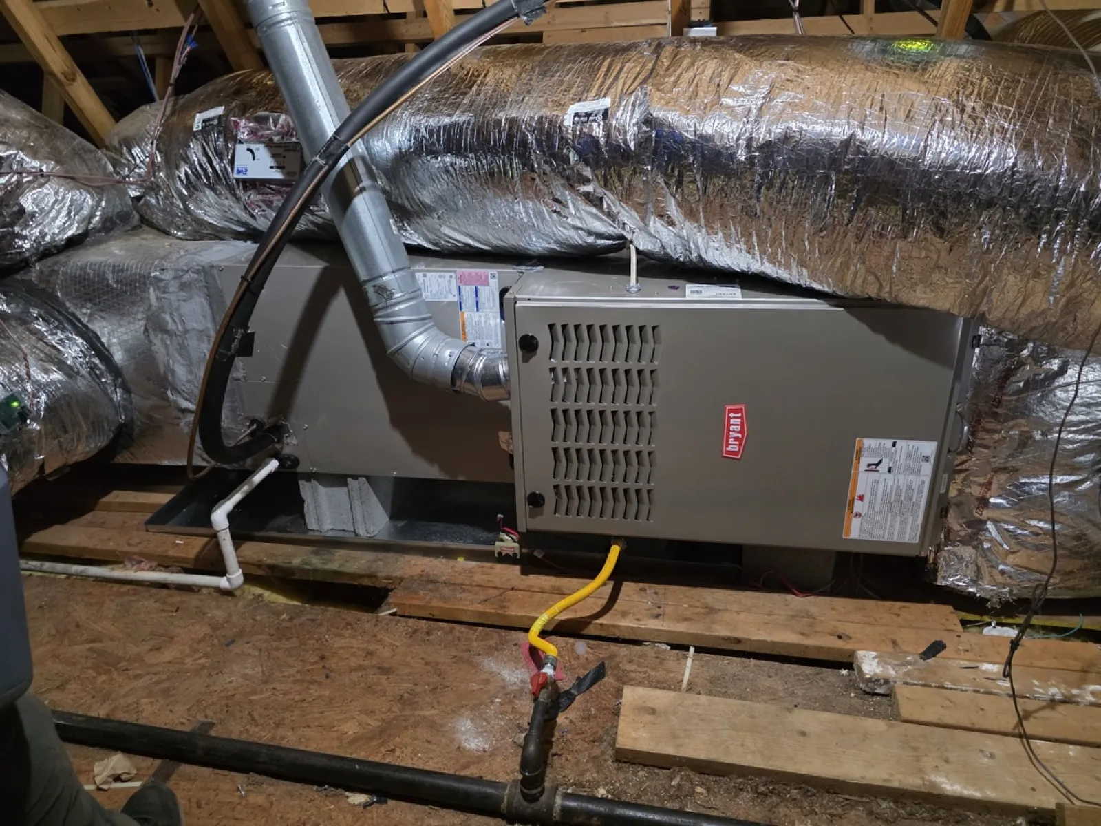 Residential HVAC system with ductwork, furnace, and ventilation components installed in an attic space.