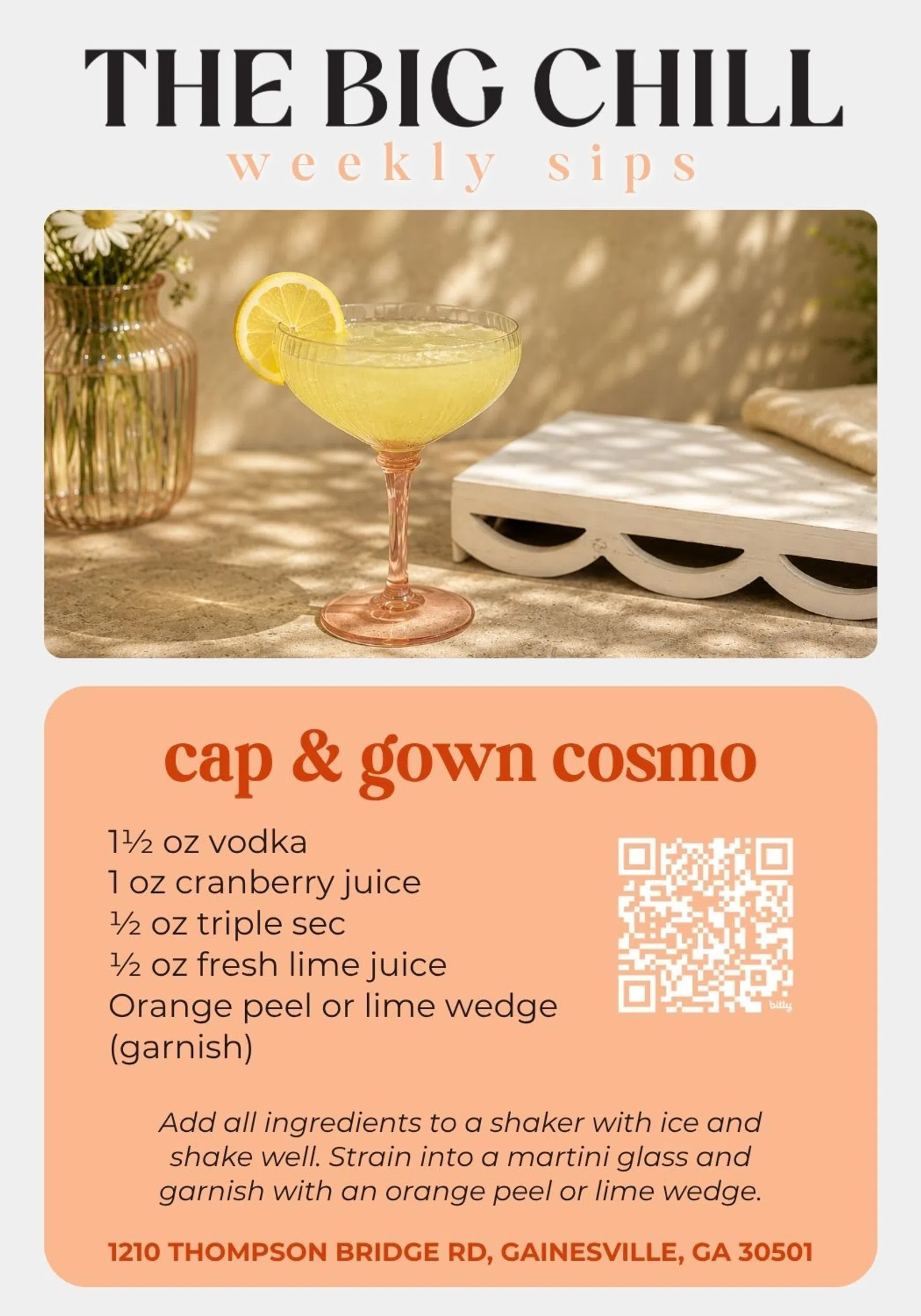 Cap & Gown Cosmo cocktail in a glass with lemon garnish and floral decor on a sunny table.