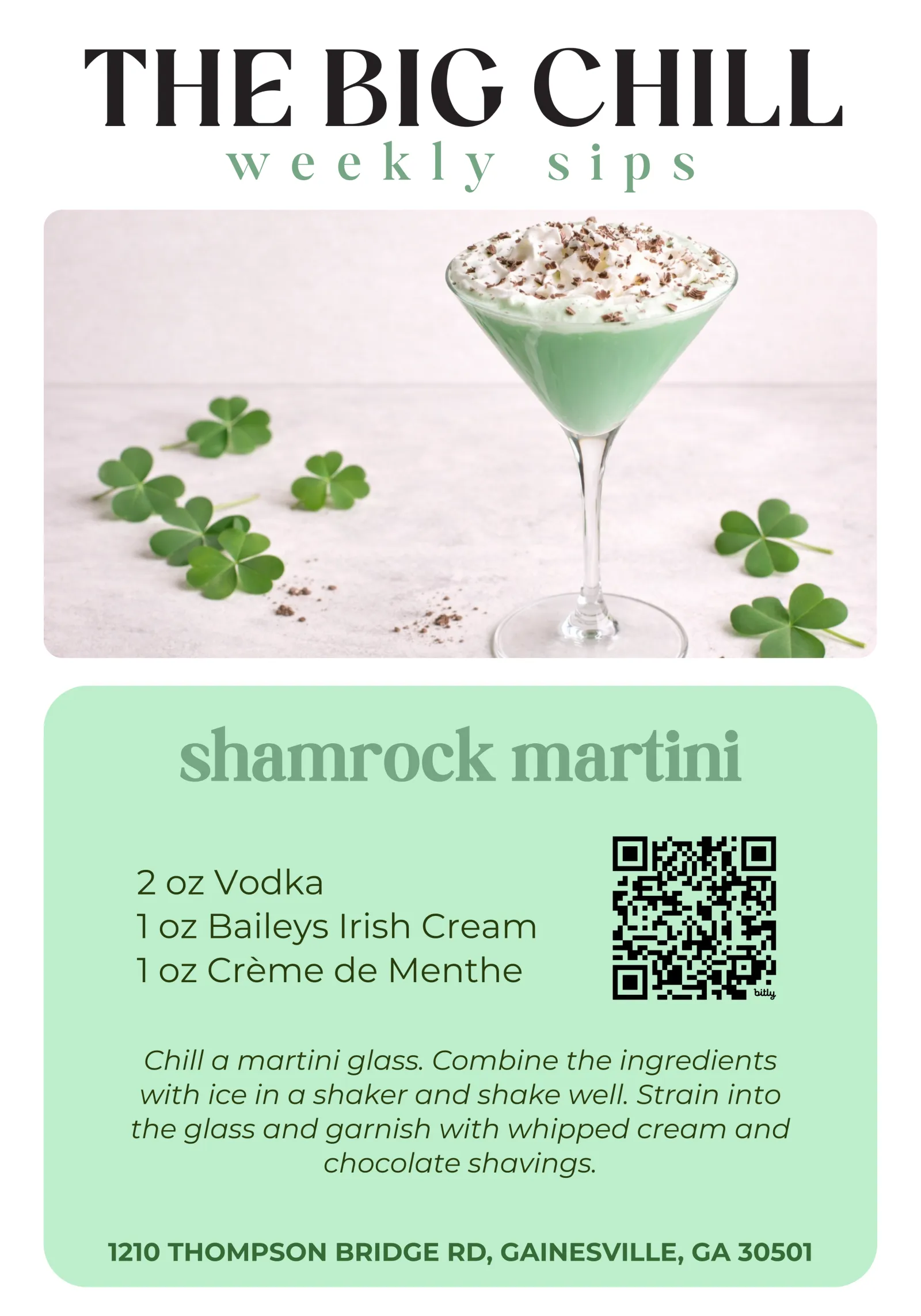 Green shamrock martini with whipped cream and chocolate shavings in a martini glass with shamrocks on white surface.