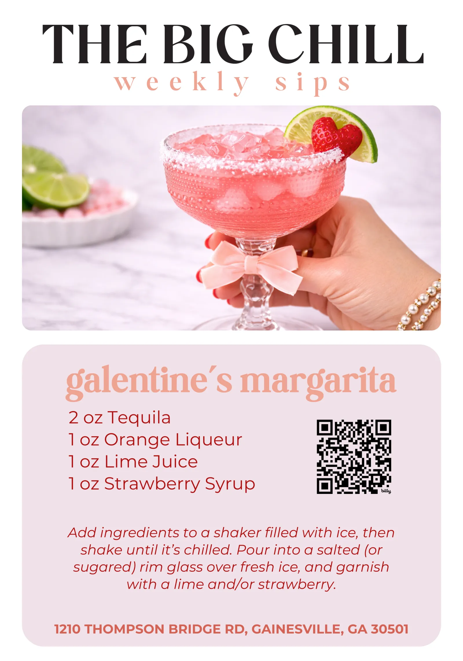 Pink Galentine's margarita in a sugar-rimmed glass garnished with lime and strawberry held by a hand with bracelet.