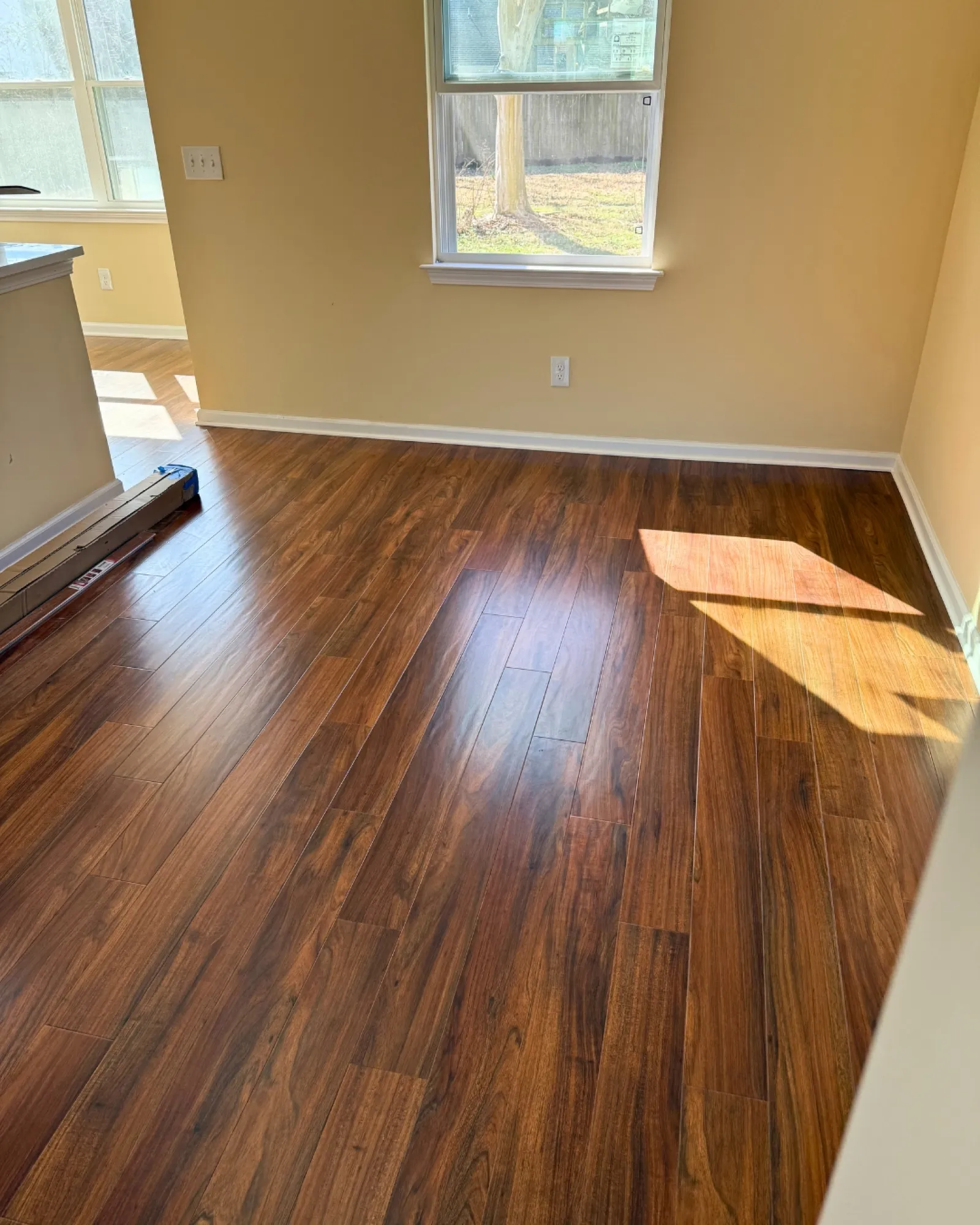 Bright, empty room showcasing new LVP flooring and natural light.