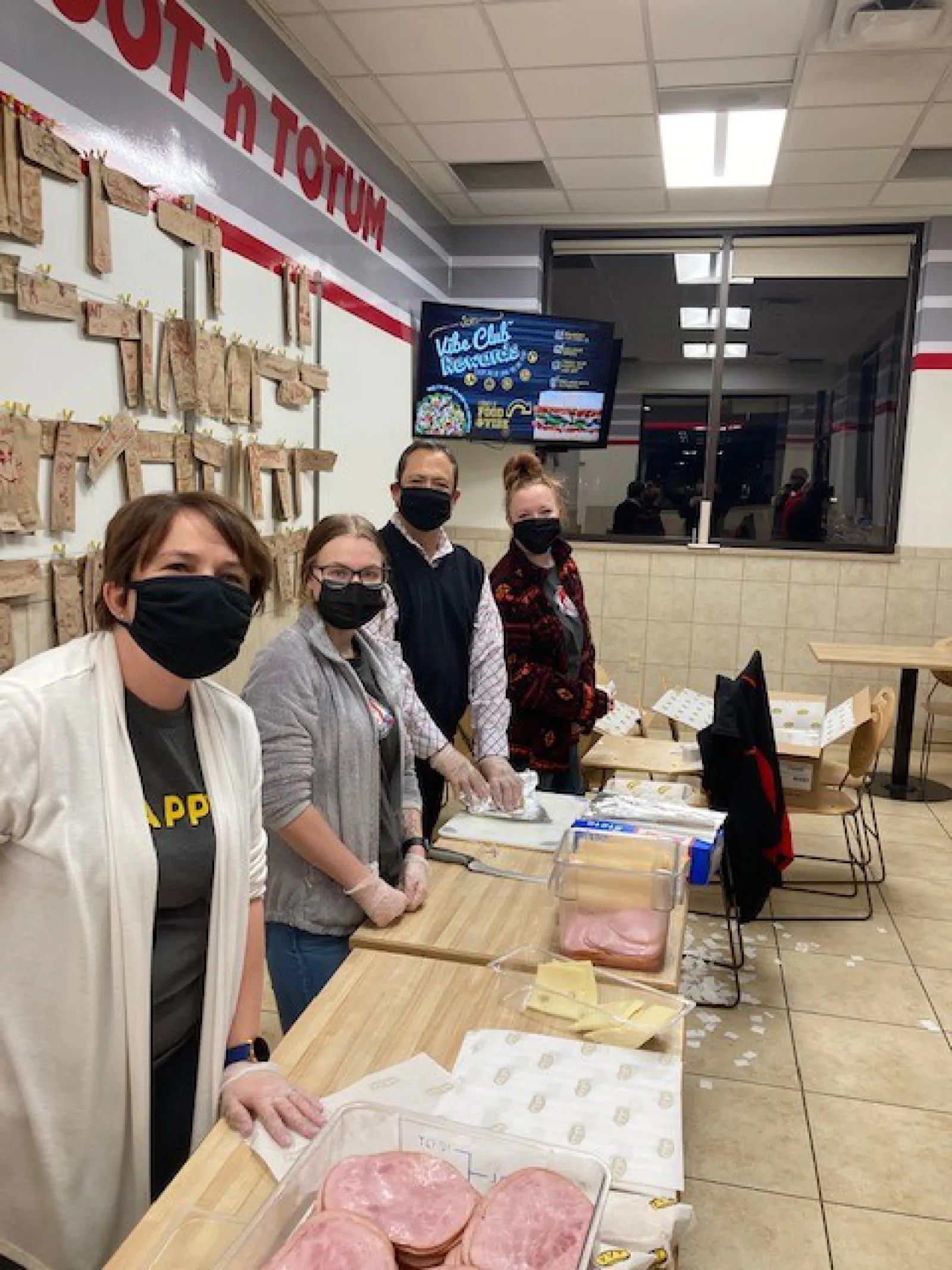 a group of people standing around a table with food on it