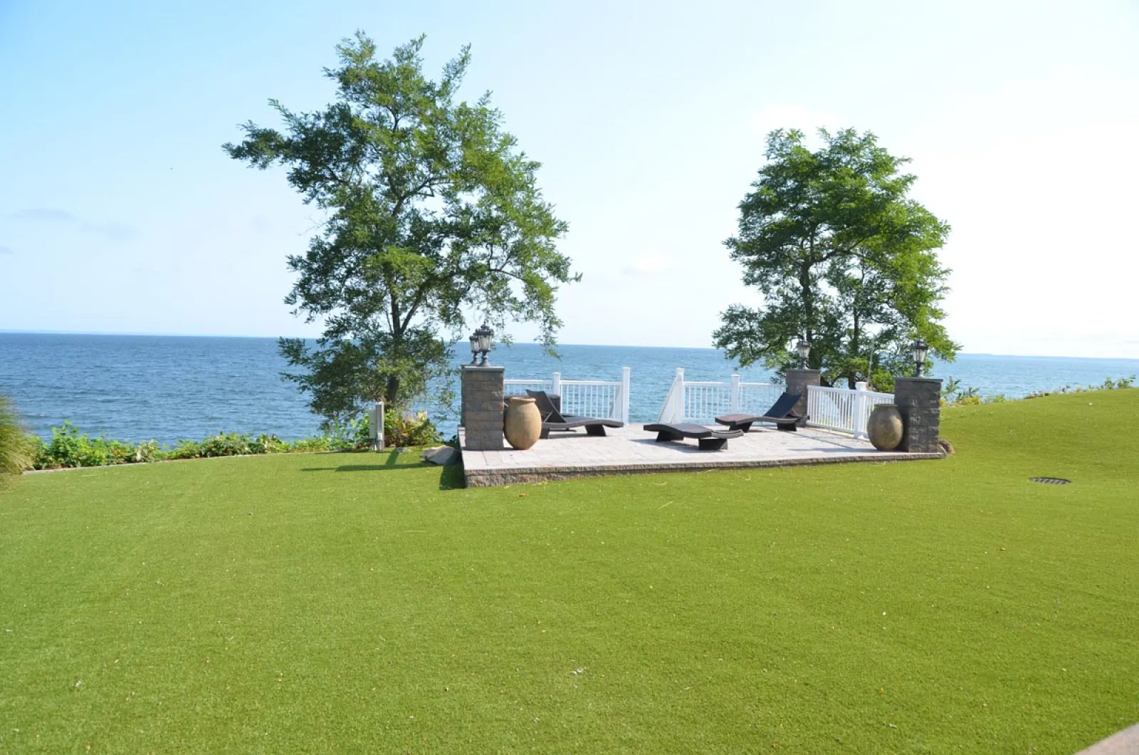 a lawn with a tree and a body of water in the background