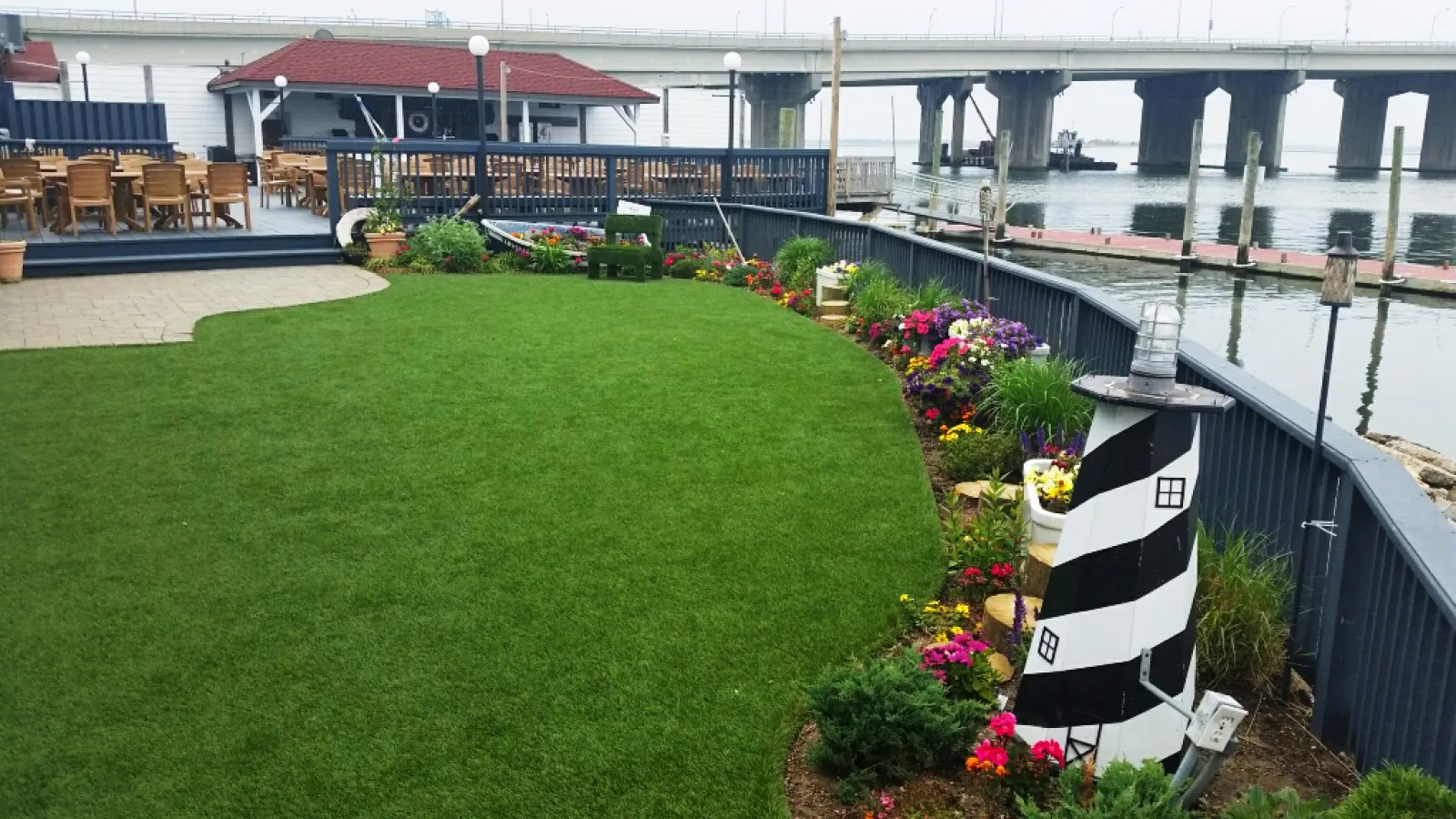 a lawn with chairs and tables by a body of water