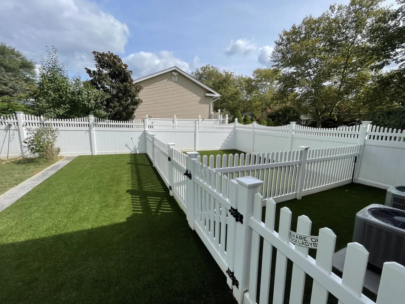 a white fence with a white picket fence and a house in the background