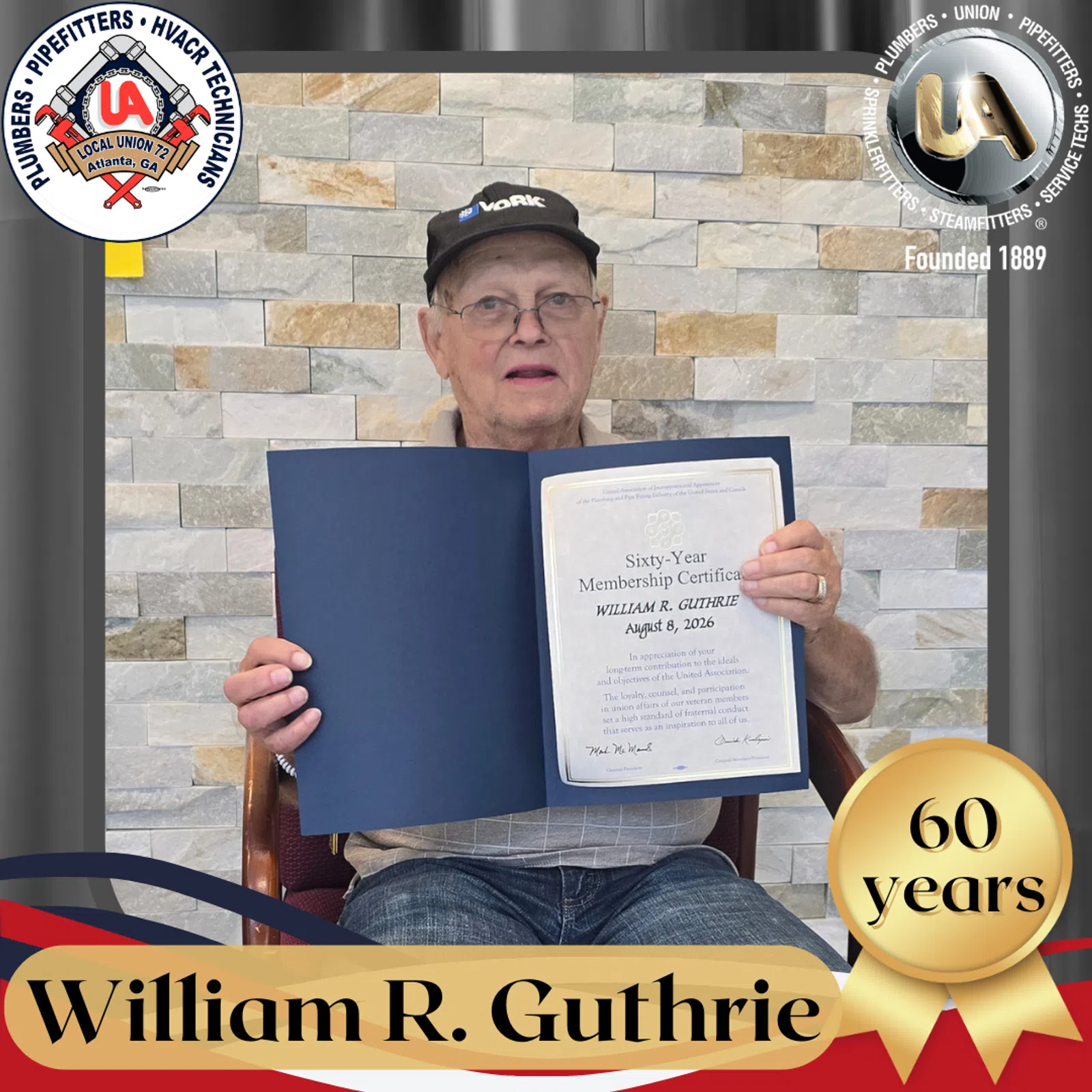 Older man holding a framed sixtieth-year membership certificate seated in front of stone wall background.
