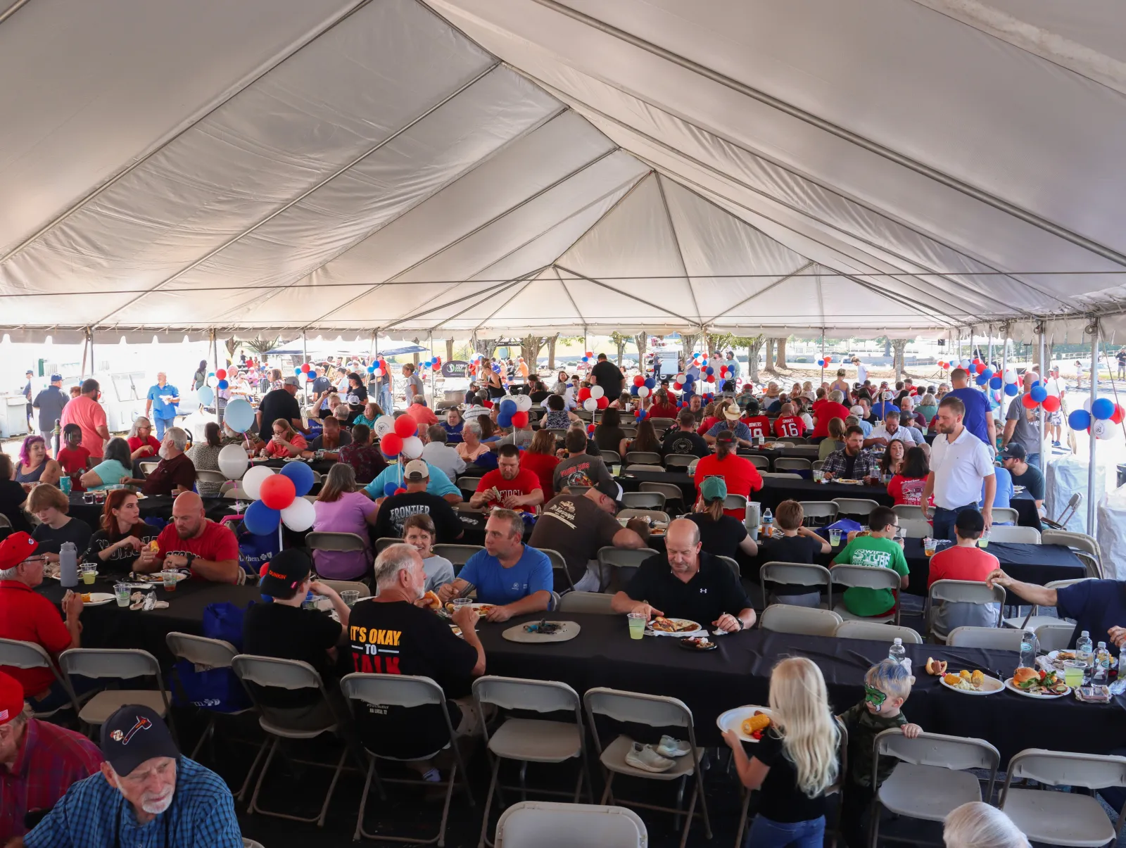 a large crowd of people sitting at tables in a tent