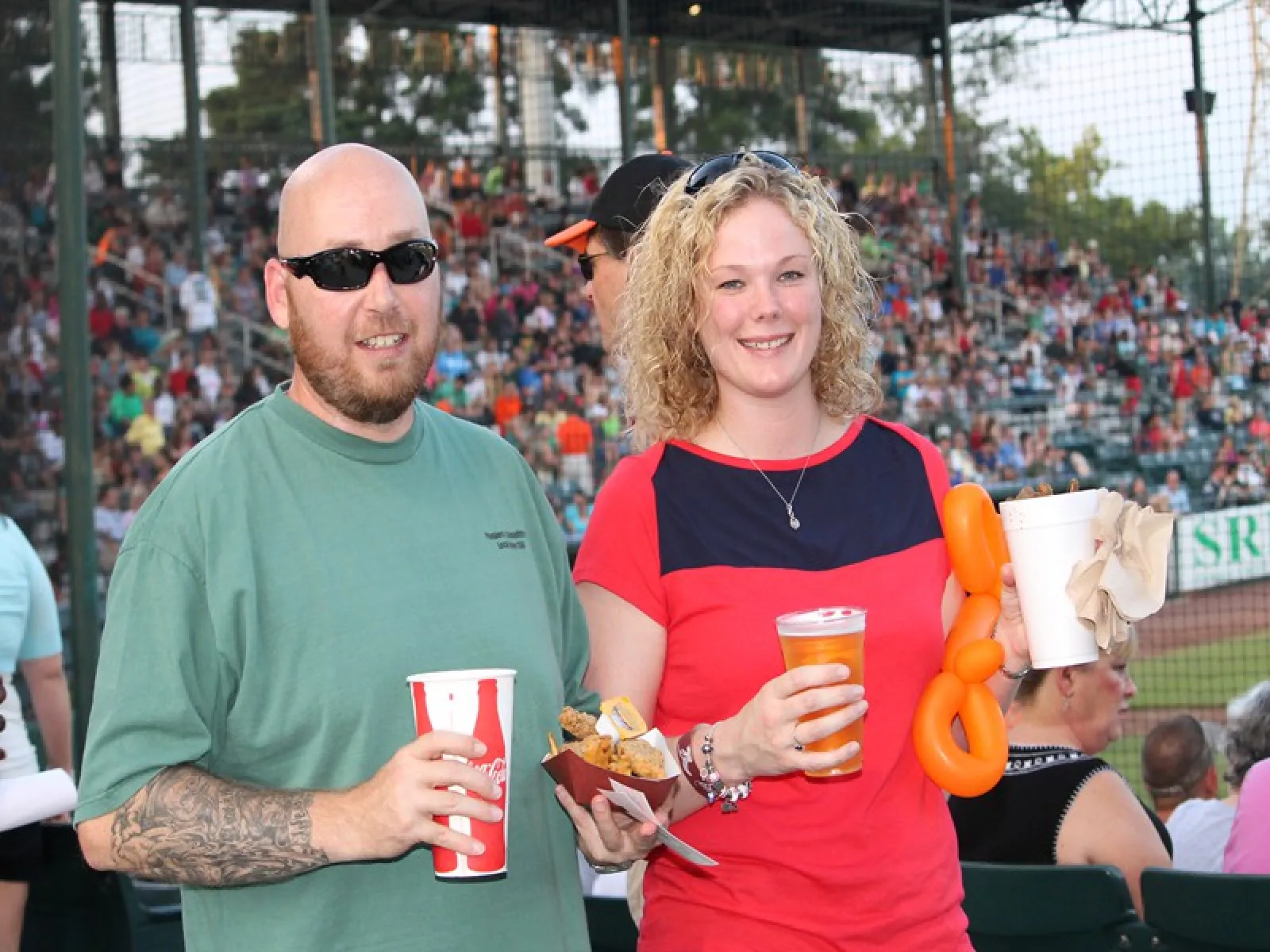 a man and woman holding drinks and a hot dog