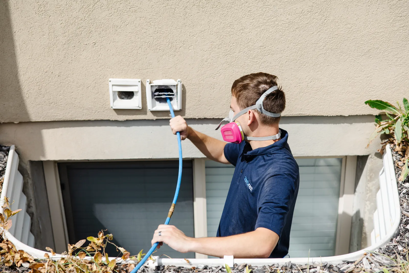 a male Zerorez employee feeding a cleaning hose into a dirty dryer vent