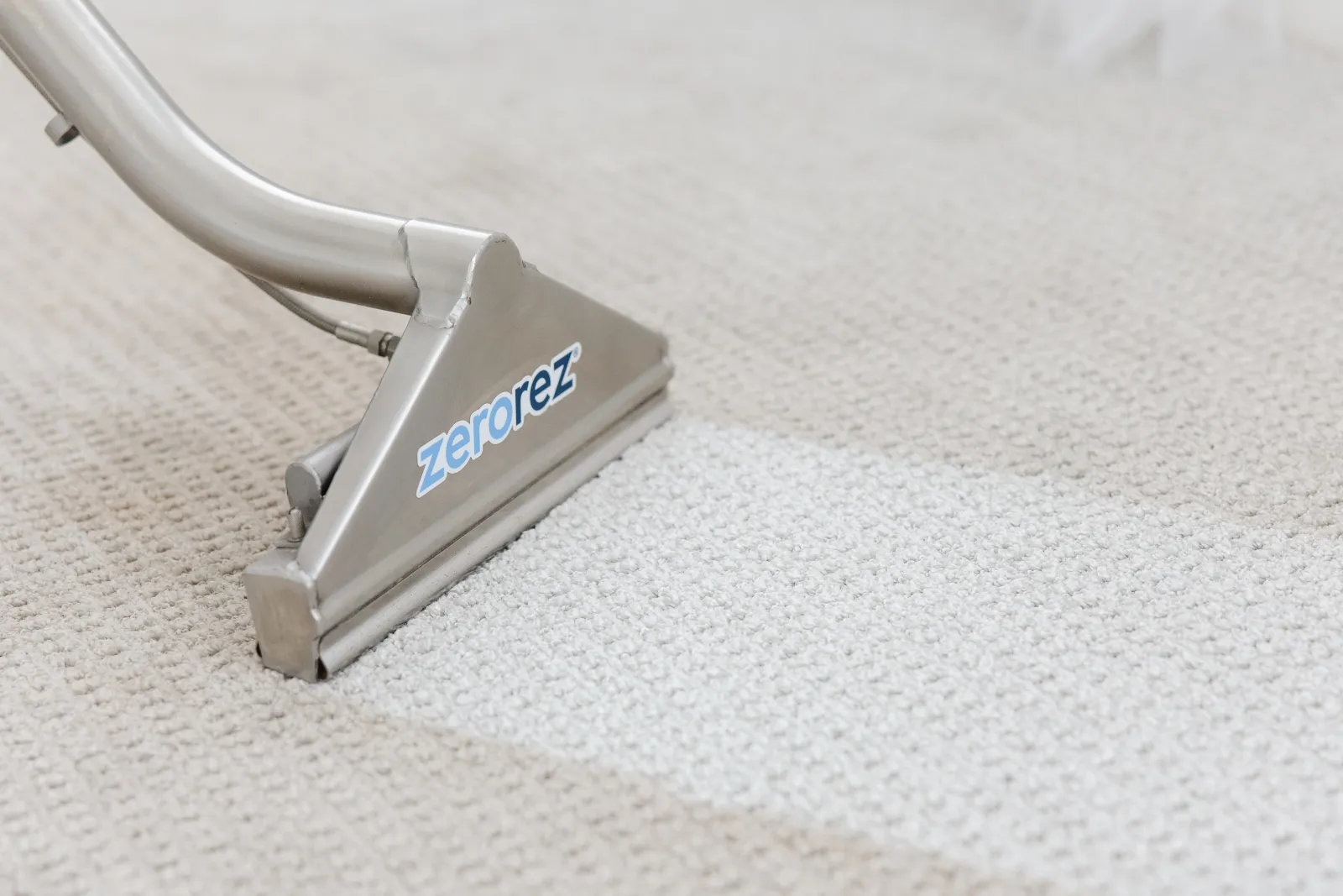 close up a Zerorez Zr Wand cleaning a gray carpet, showing a white stripe where its high alkaline Zr Water cleaned a stripe of the carpet clean