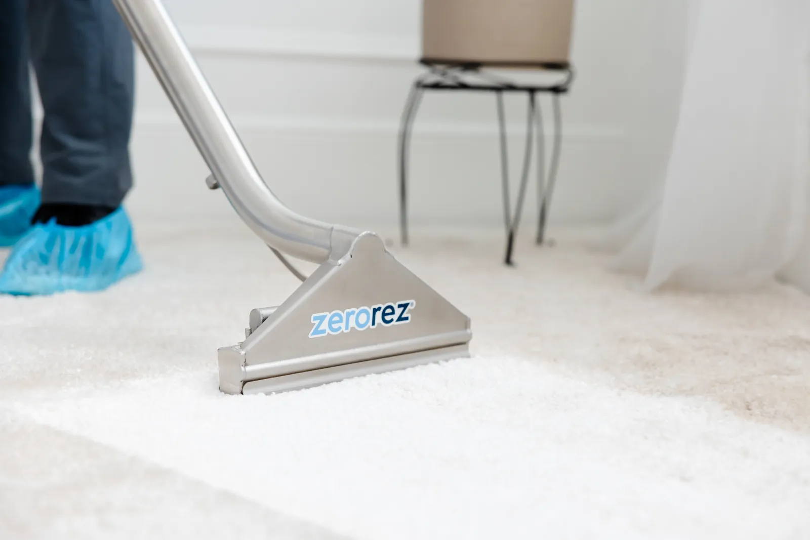 Zerorez® Zr® Wand being used by a technician with blue booties on to clean a white carpet