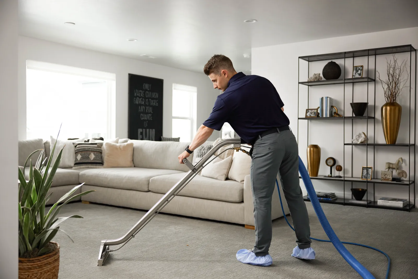 man with a cleaning wand cleaning tan carpet in a living room