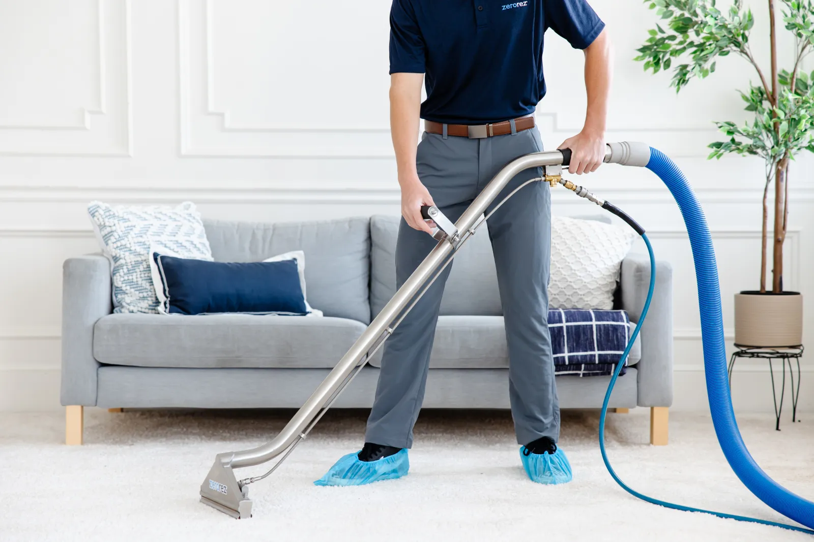 carpet technician cleaning cream carpet with blue couch 