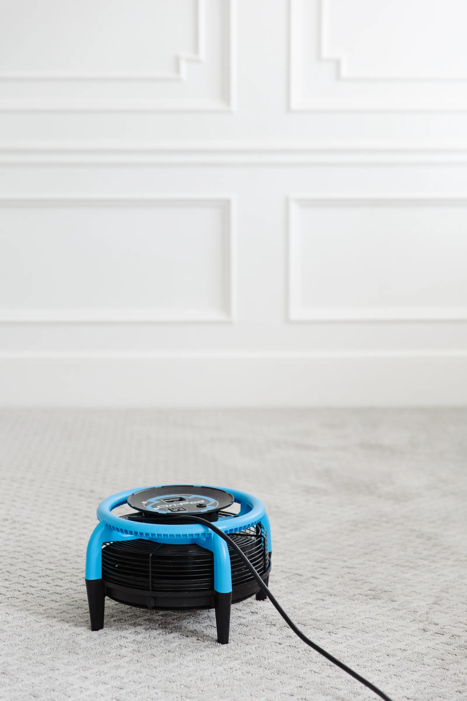 black and blue Dri-Pod air mover floor fan to help dry wet flooded carpet