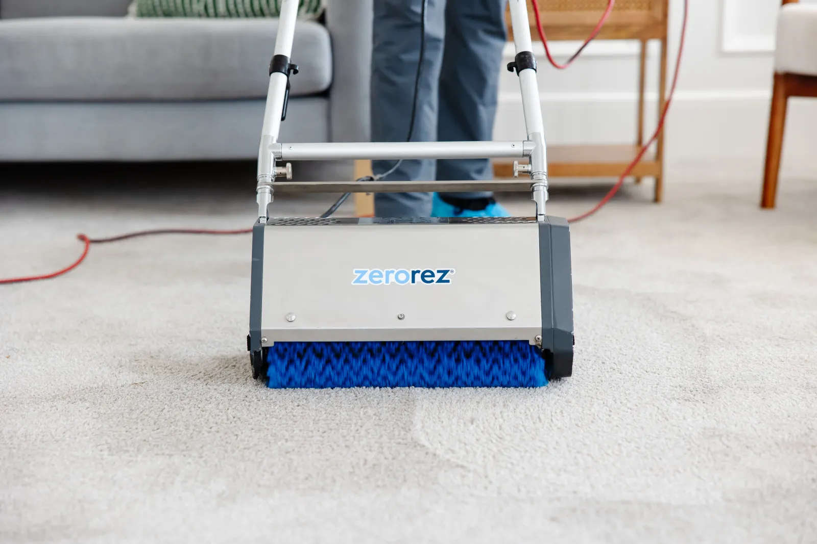 Close up of the counter rotating brushes of a Zr™ Lifter from Zerorez<sup>®</sup> being used on a white carpet, making its fibers fluffy and kicking up all the embedded hair and dirt deep in the carpet's fibers