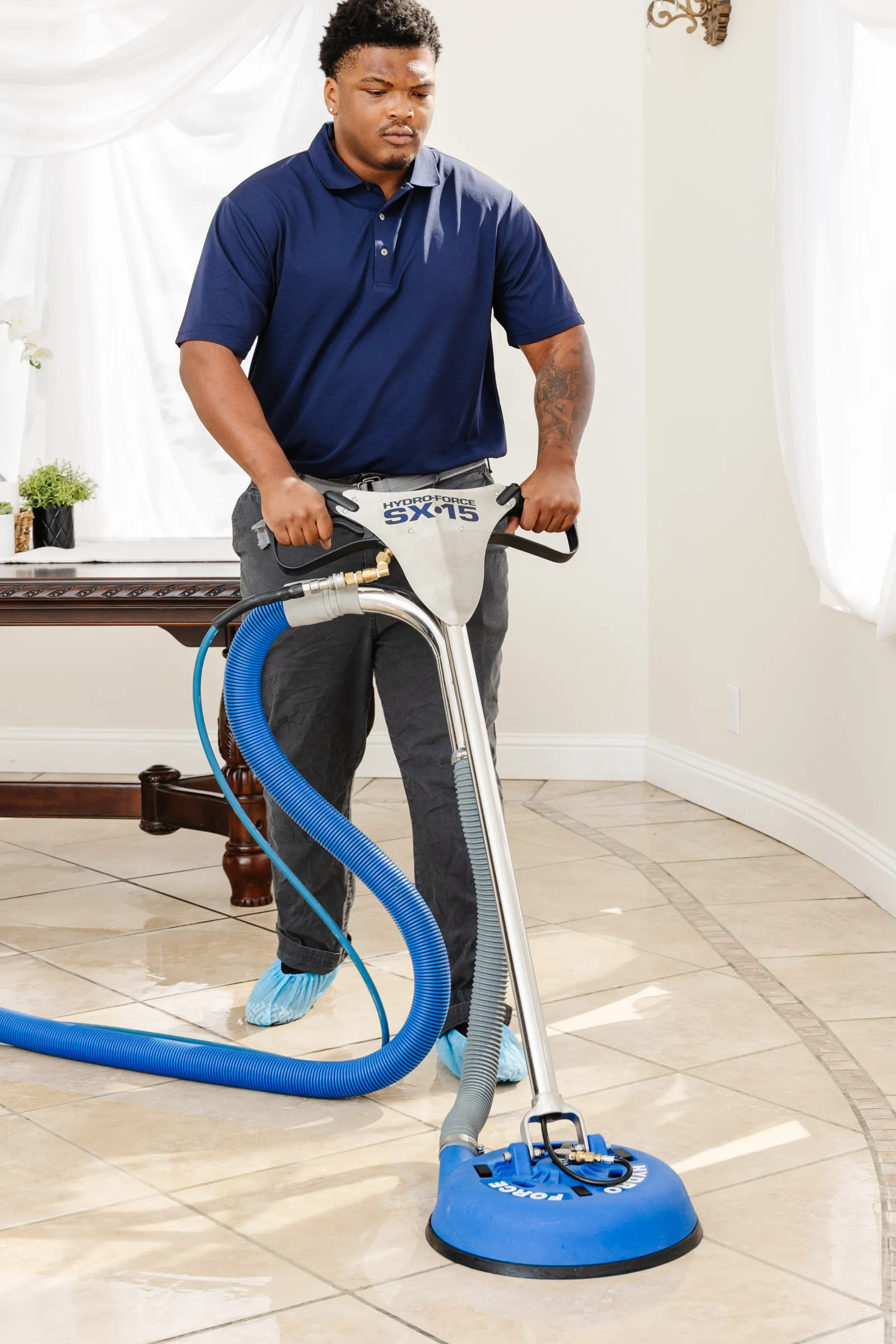 male Zerorez® technician using a tile and grout cleaning tool to clean beige tile flooring in a dining room