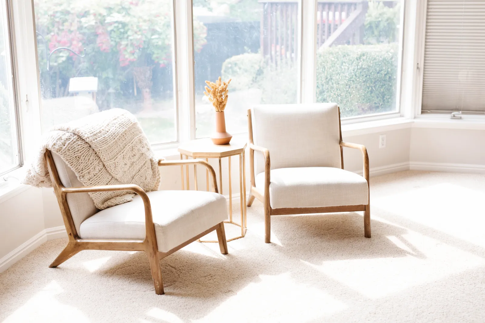 two wood and cream chairs on carpet with end table and vase