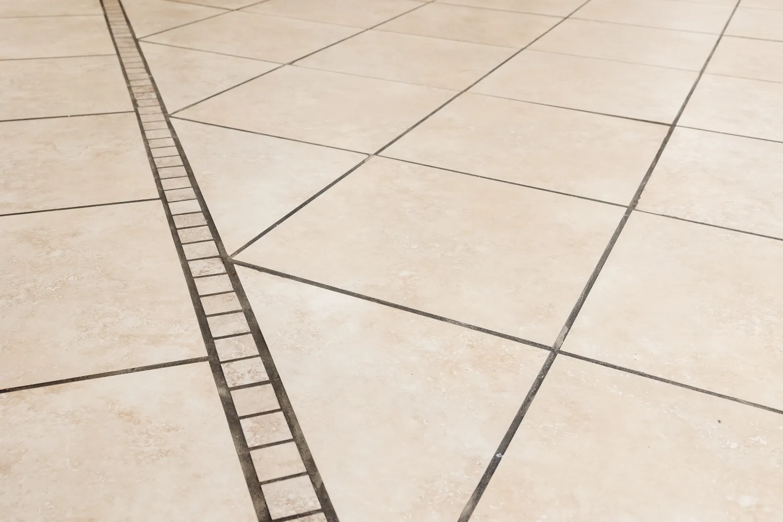 Close up of dirty dark black tile grout lines with beige tiles