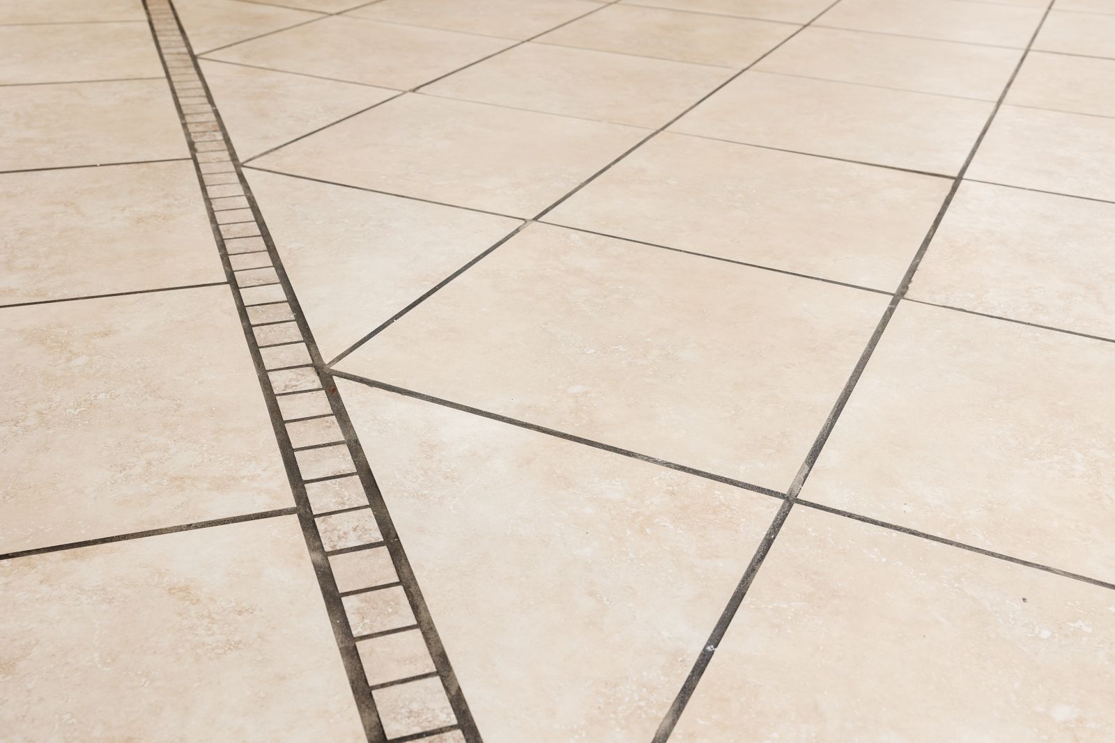 Close up of dirty dark black tile grout lines with beige tiles