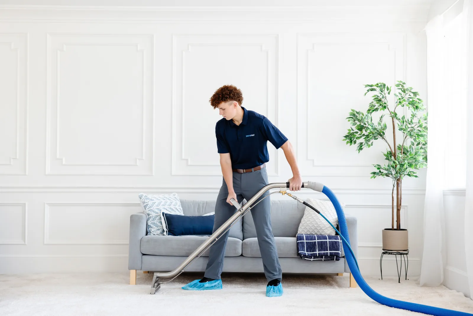 Male Zerorez carpet cleaning technician cleaning with the Zr Wand to get a white carpet in a living room clean