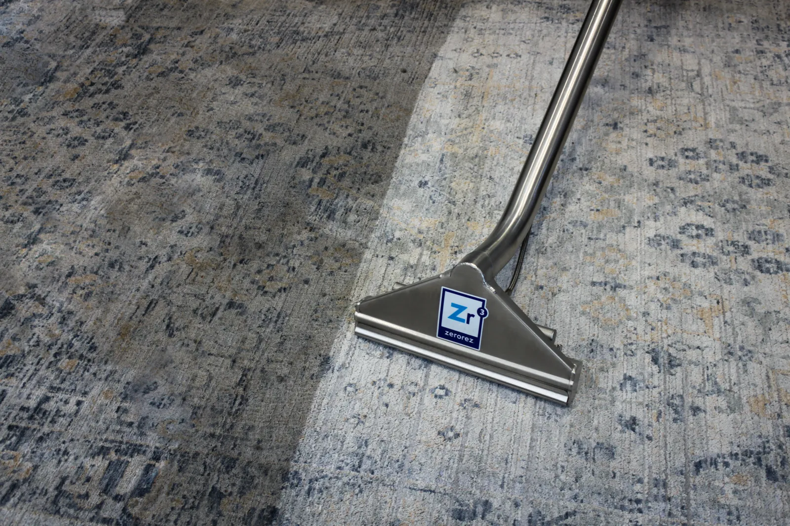 close up of a Zerorez Zr™ Wand on the clean side of a wool rug with the left side still visibly darker and dirtier