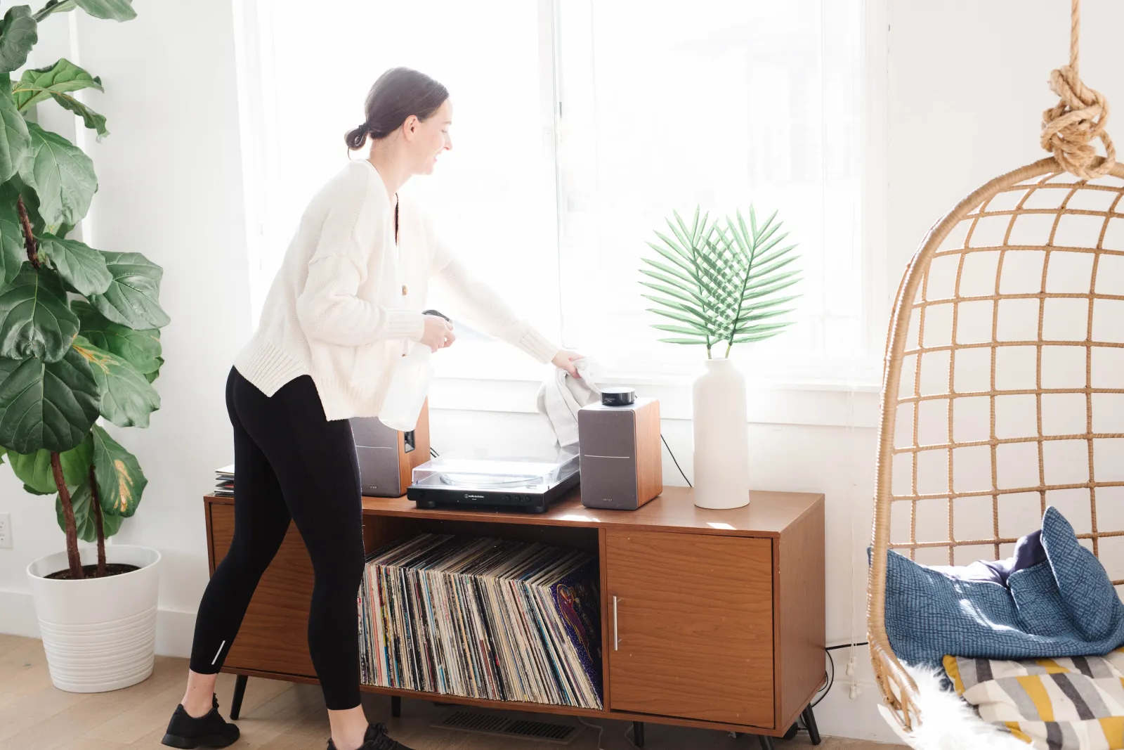 woman dusting a book shelf in a room with a record player