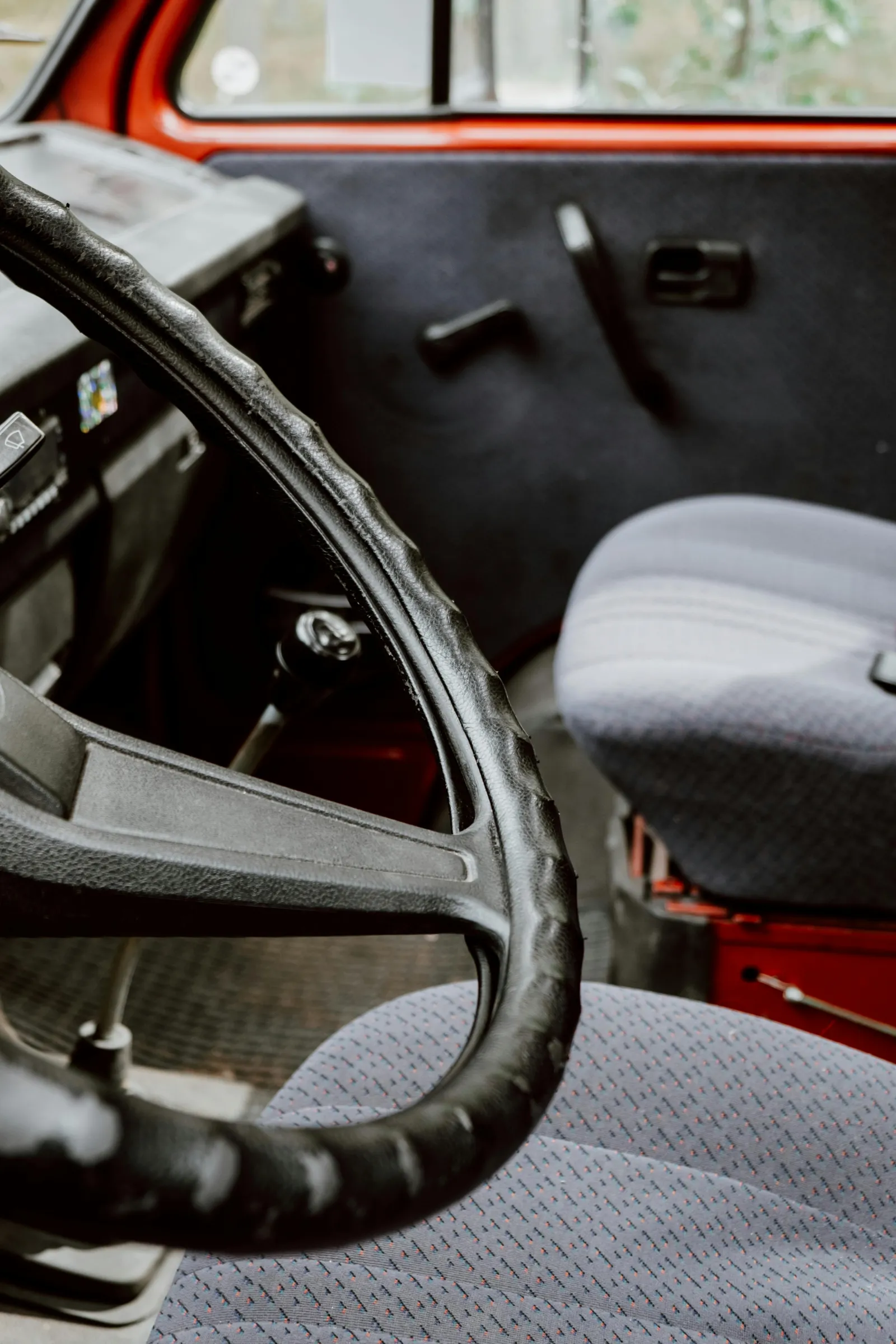 close up of inside of an older dirty car front seat and floor carpet and seat upholstery