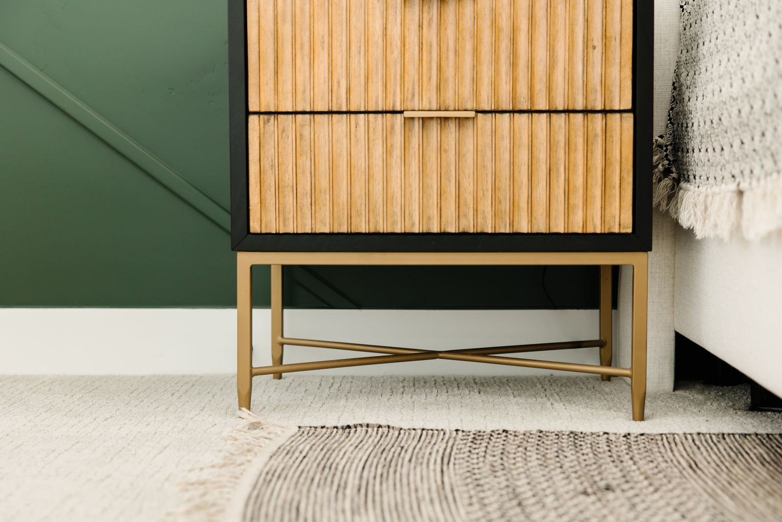 small area rug on top of a white carpet with a green wall and sideboard nightstand